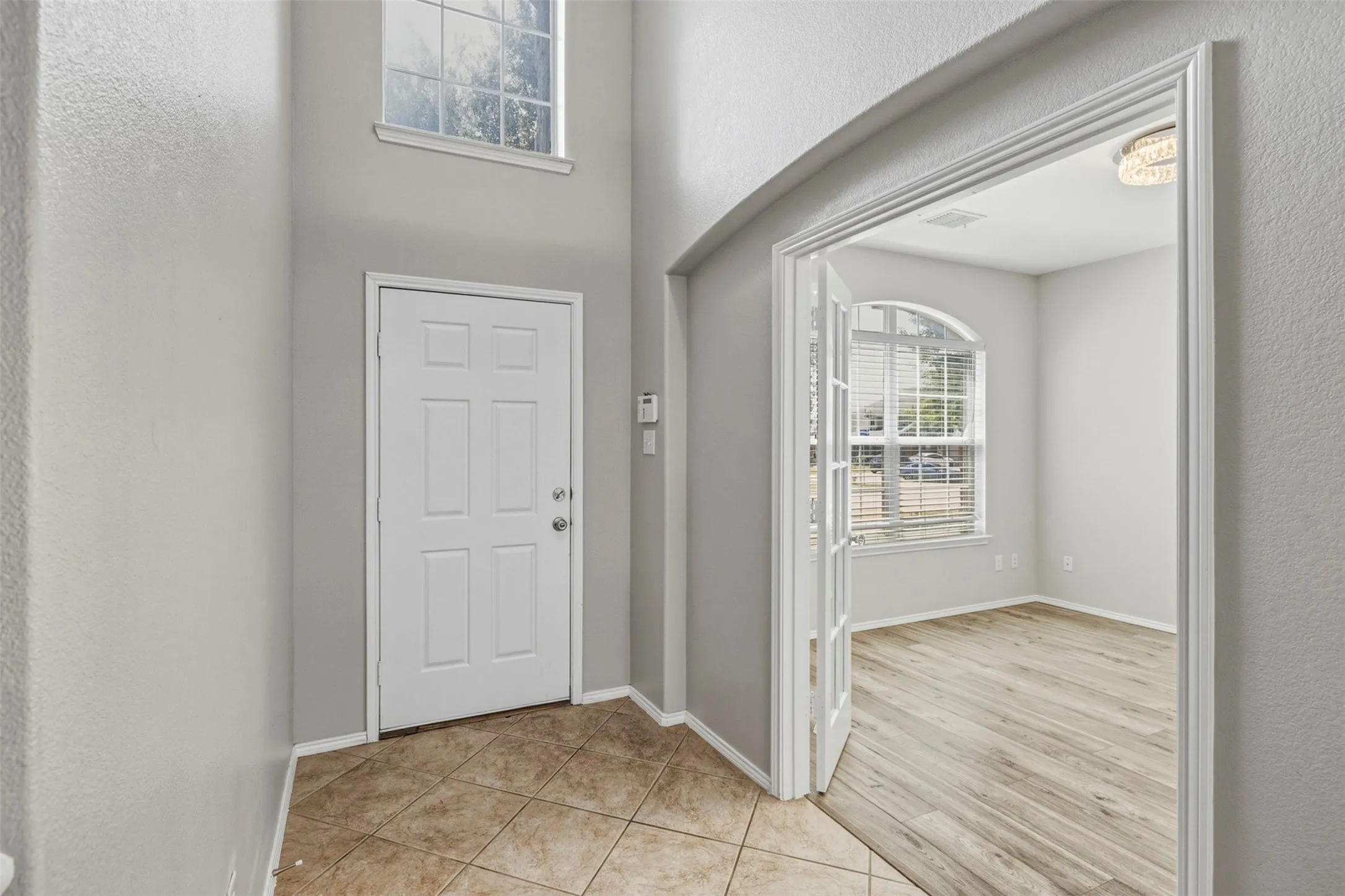 Two-story foyer with high ceilings, ceramic tile flooring, and a six-panel entry door