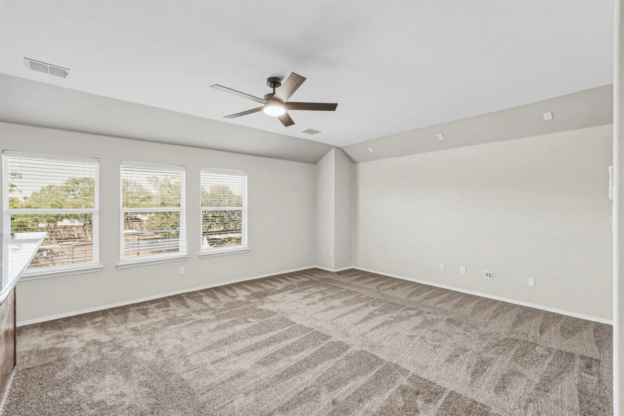 Carpeted interior with multiple windows, a ceiling fan, and recessed lighting