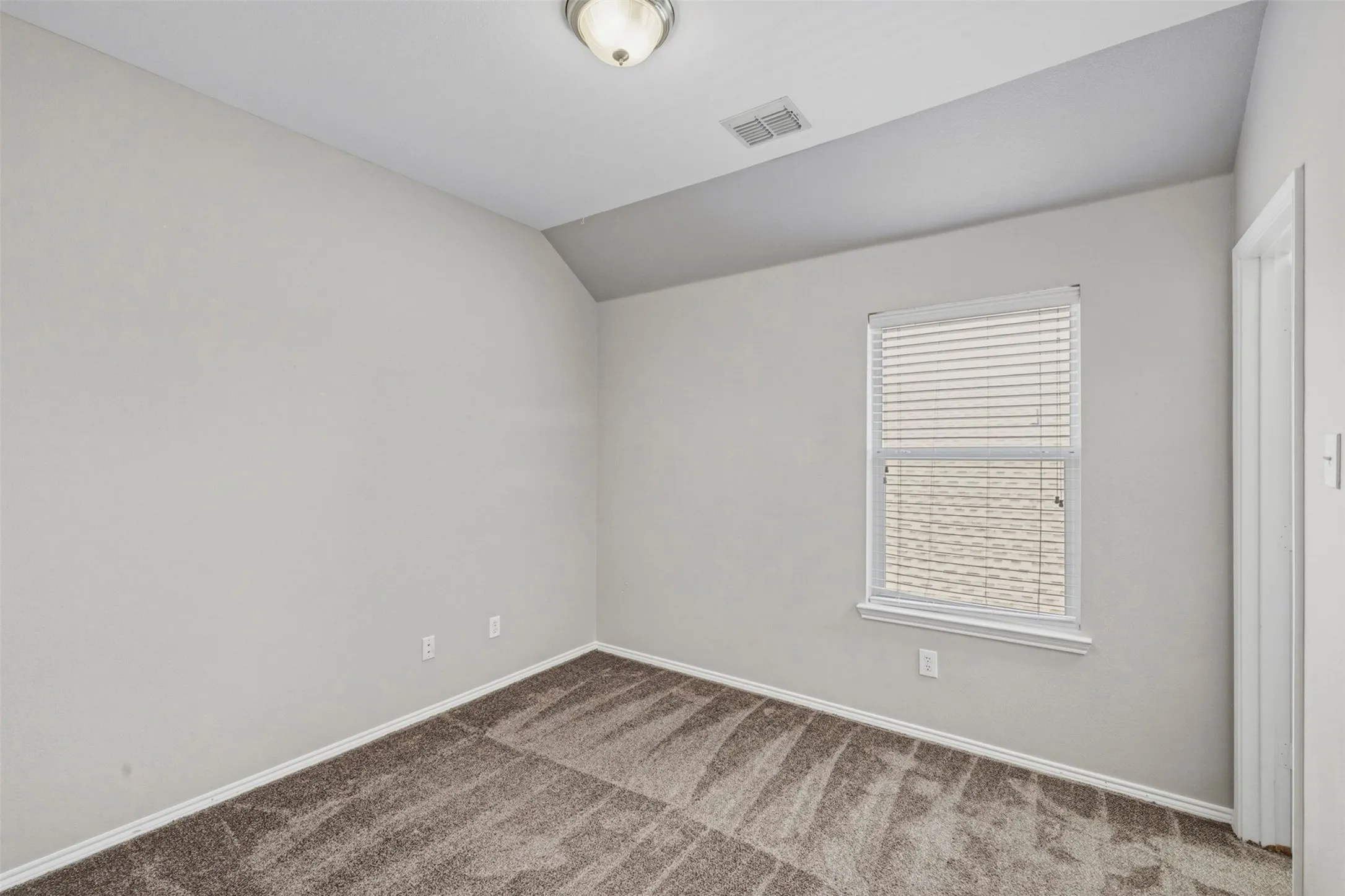 Textured carpeting, neutral wall finishes, window with blinds, and a semi-flush mount ceiling fixture