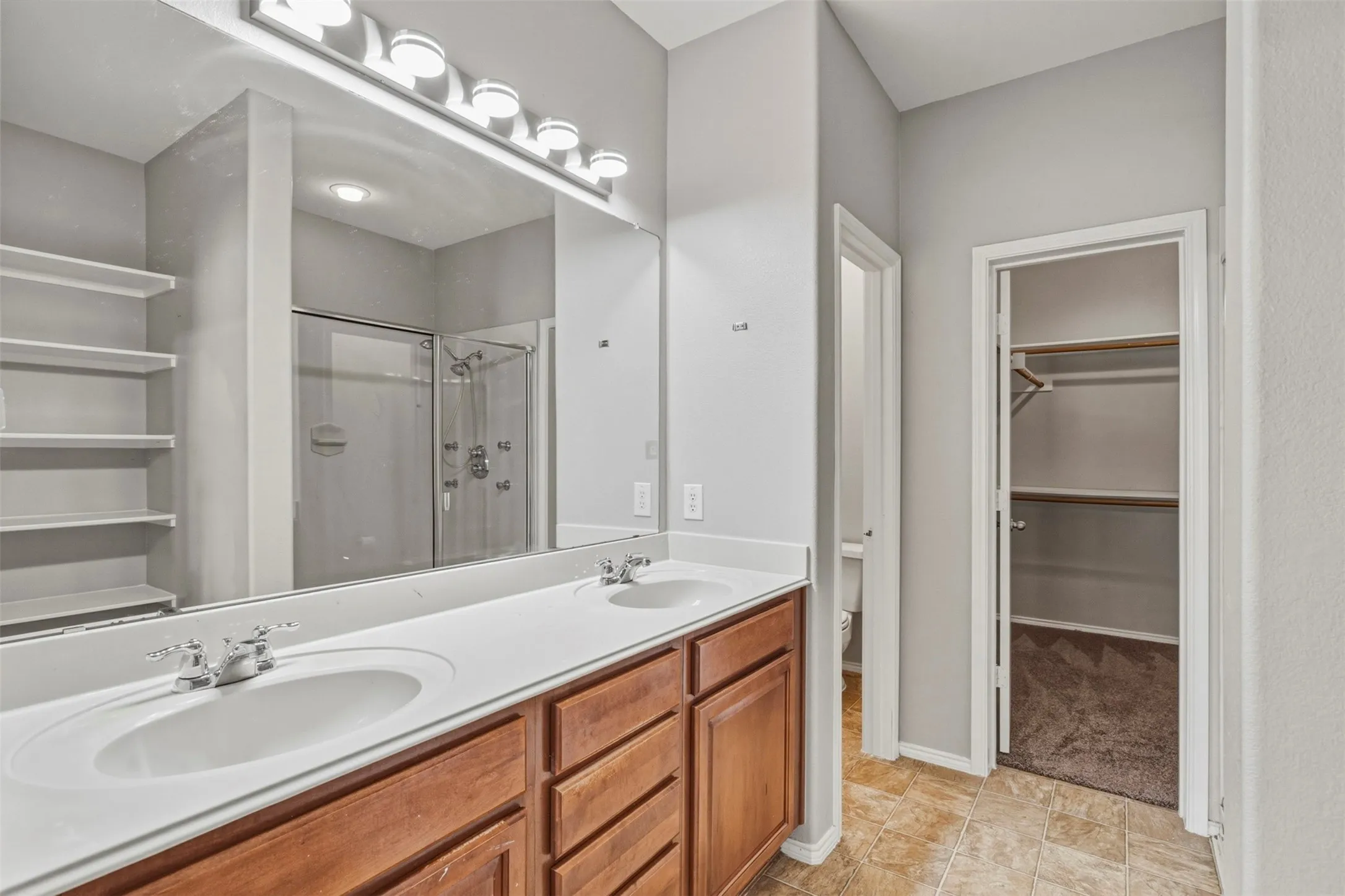 Dual vanity with white countertops and wood-finish cabinetry