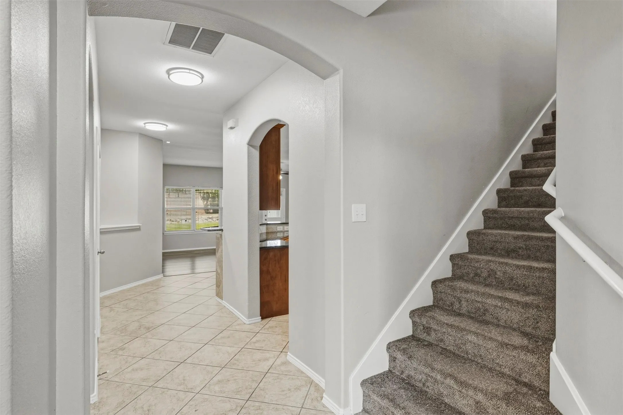 Arched doorways, tile flooring, wall-to-wall carpeting on stairs, recessed lighting, and a built-in cabinet with a countertop