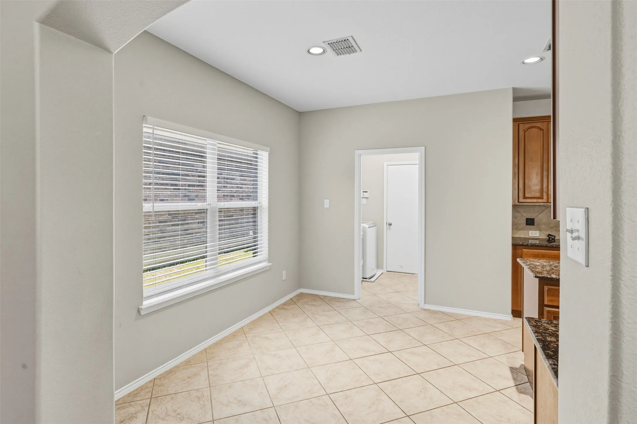 Recessed lighting, tiled flooring, window with horizontal blinds, neutral wall paint, and a pass-through opening