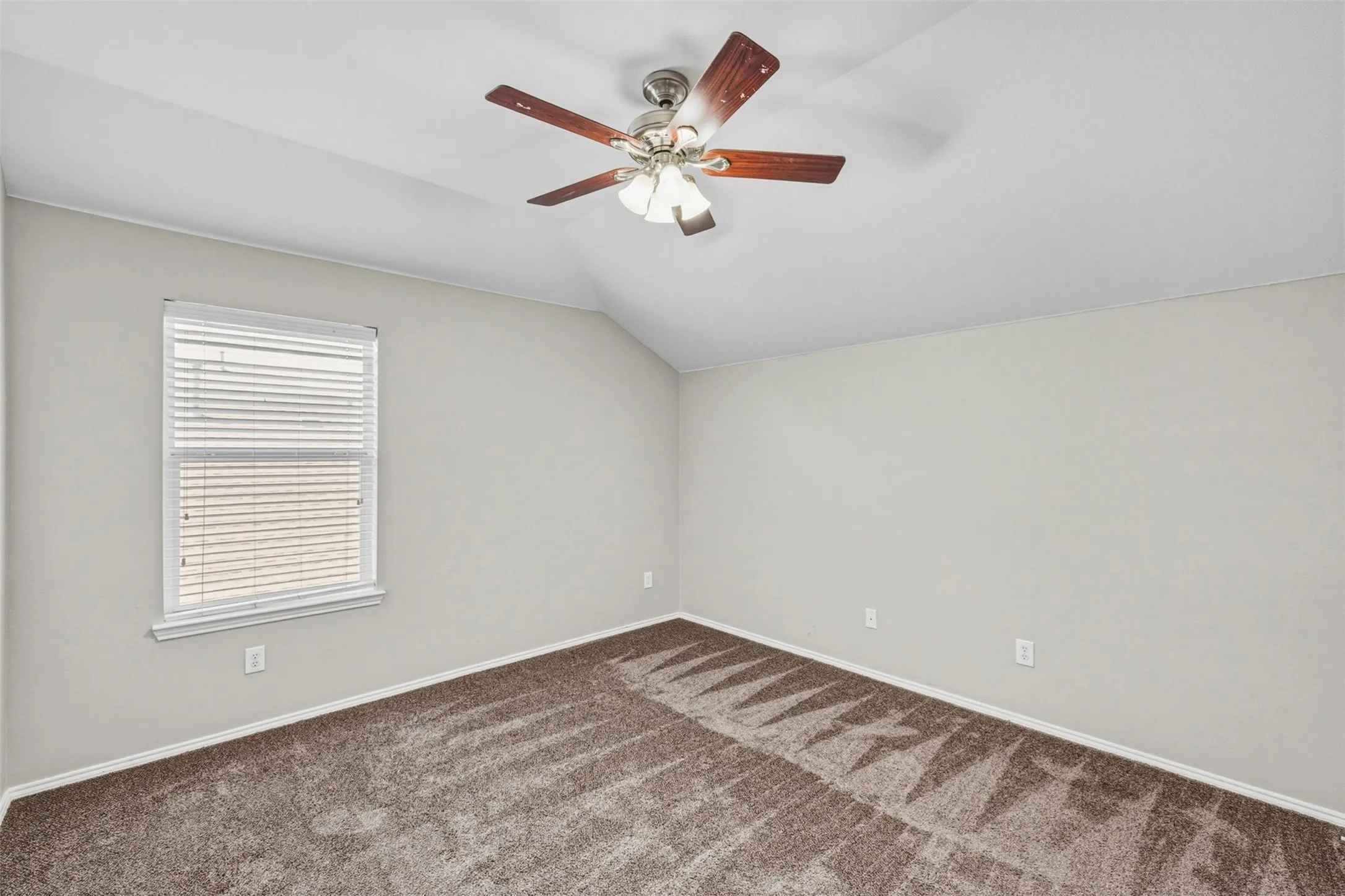 Vaulted ceiling with a ceiling fan, neutral wall paint, and plush carpet flooring