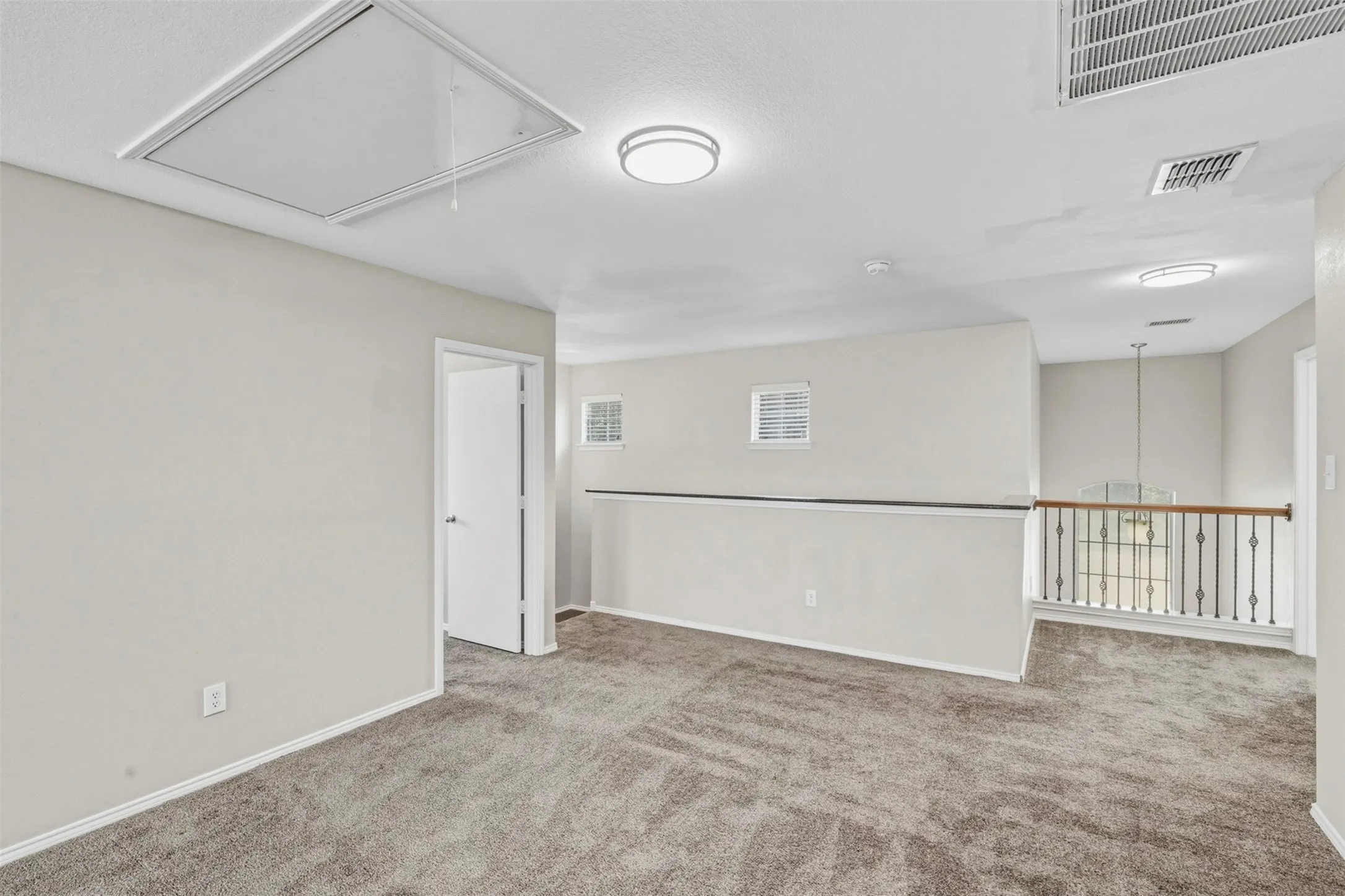 Carpeted flooring, recessed lighting, white interior door, white walls, and a wrought iron and wood handrail