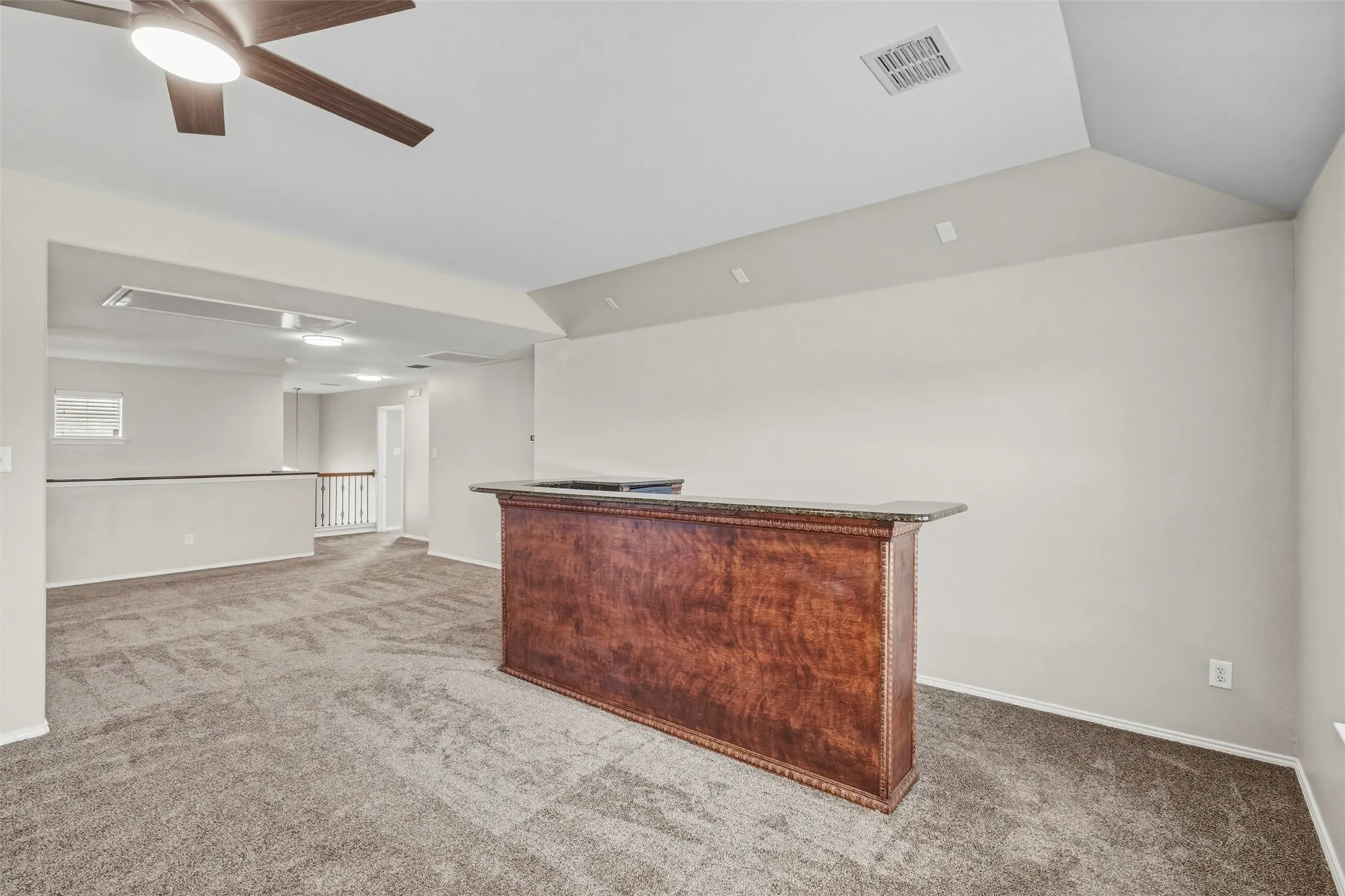 Built-in bar with stone countertop, wood-finish paneling, and elevated ceiling
