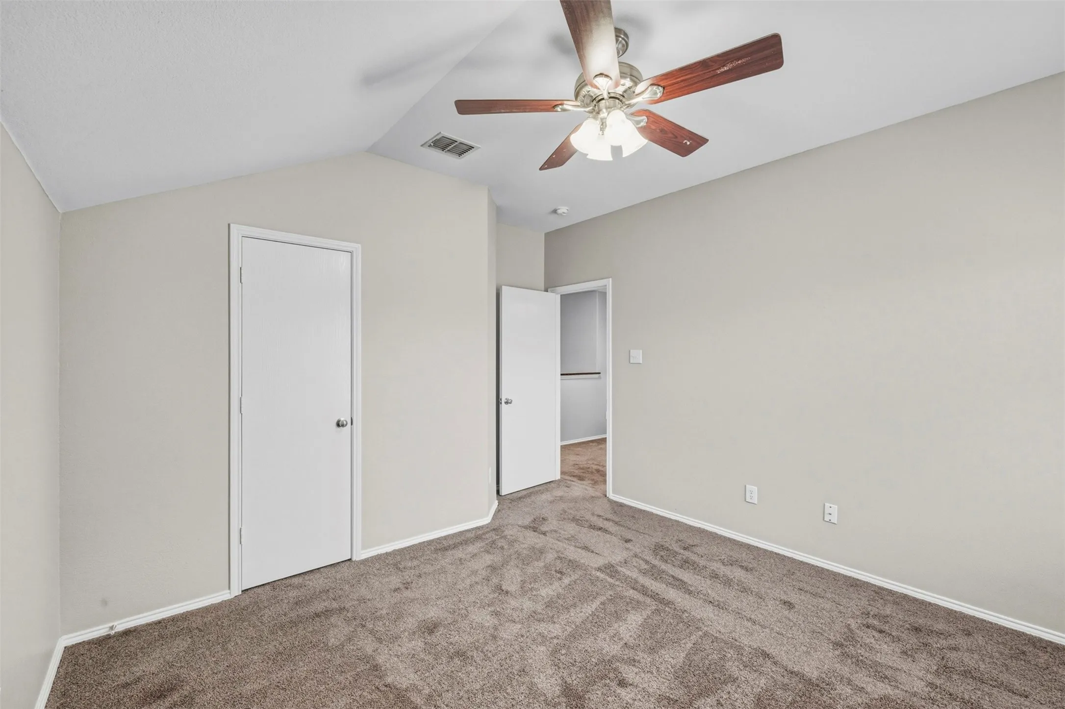 Vaulted ceiling with a ceiling fan, neutral wall color, and brown carpeting