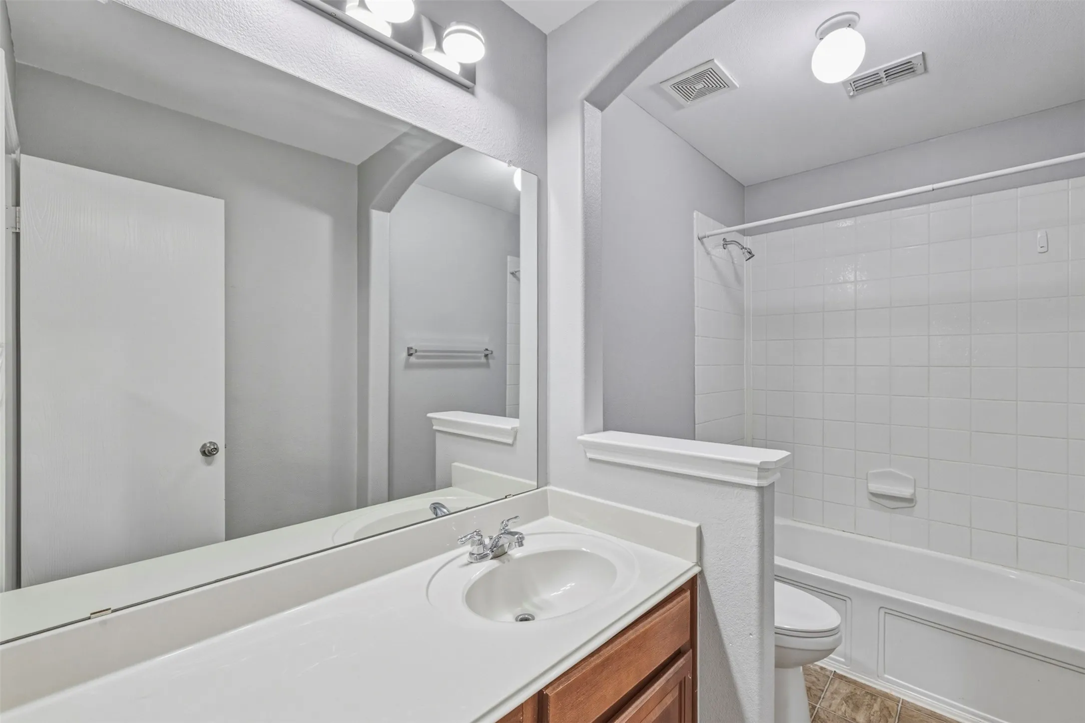 Integrated vanity with an undermount sink, wood-finish cabinetry, and a full-width mirror