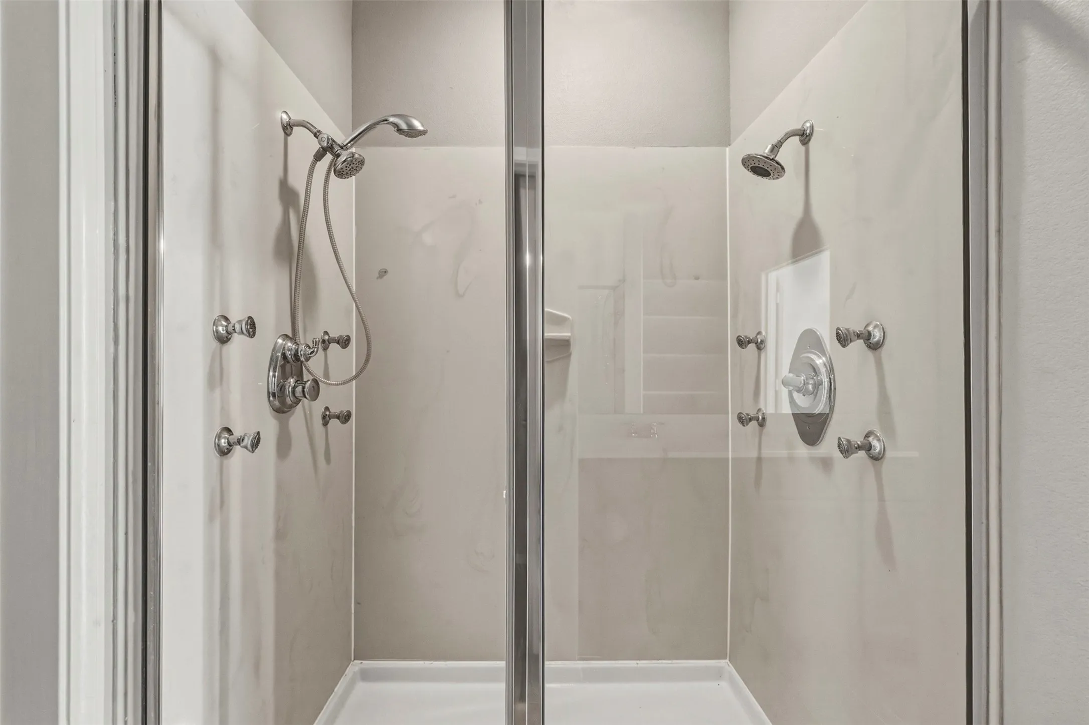 Spacious shower enclosure with dual shower heads, glass paneling, and brushed nickel fixtures