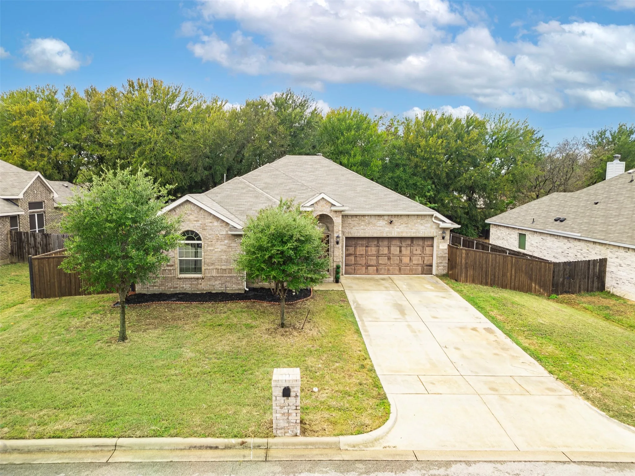 Brick exterior with an arched entry, a concrete driveway, and a two-car garage with a wood-finish door