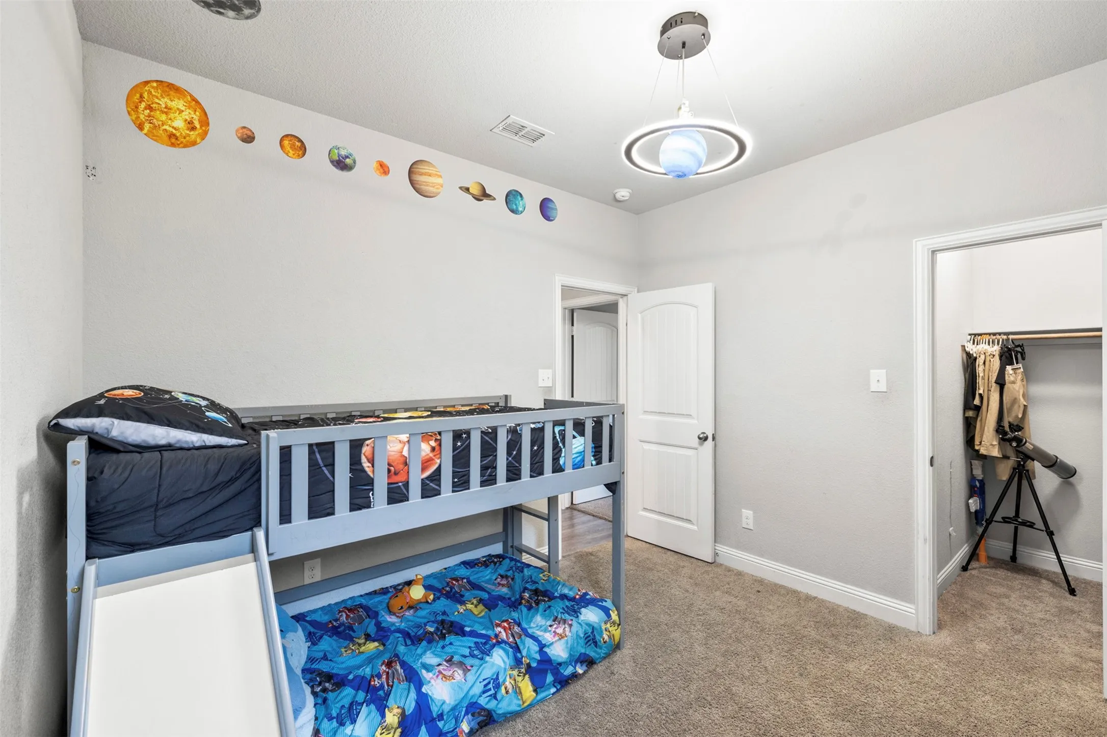 Neutral wall color, carpeted flooring, white interior door, recessed lighting, and a contemporary pendant light fixture