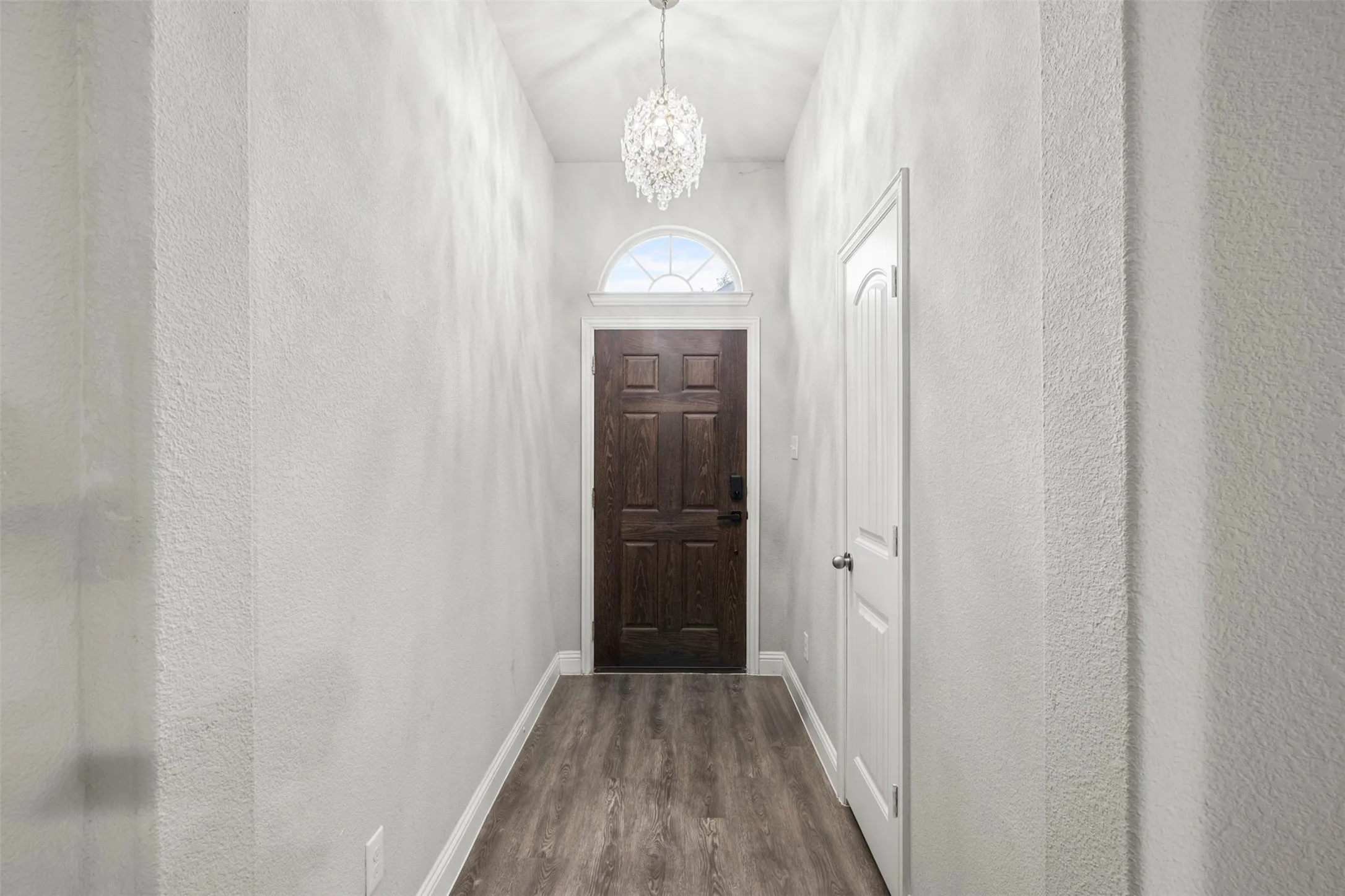 Entryway featuring wood-finish flooring, vaulted ceiling, and a crystal chandelier