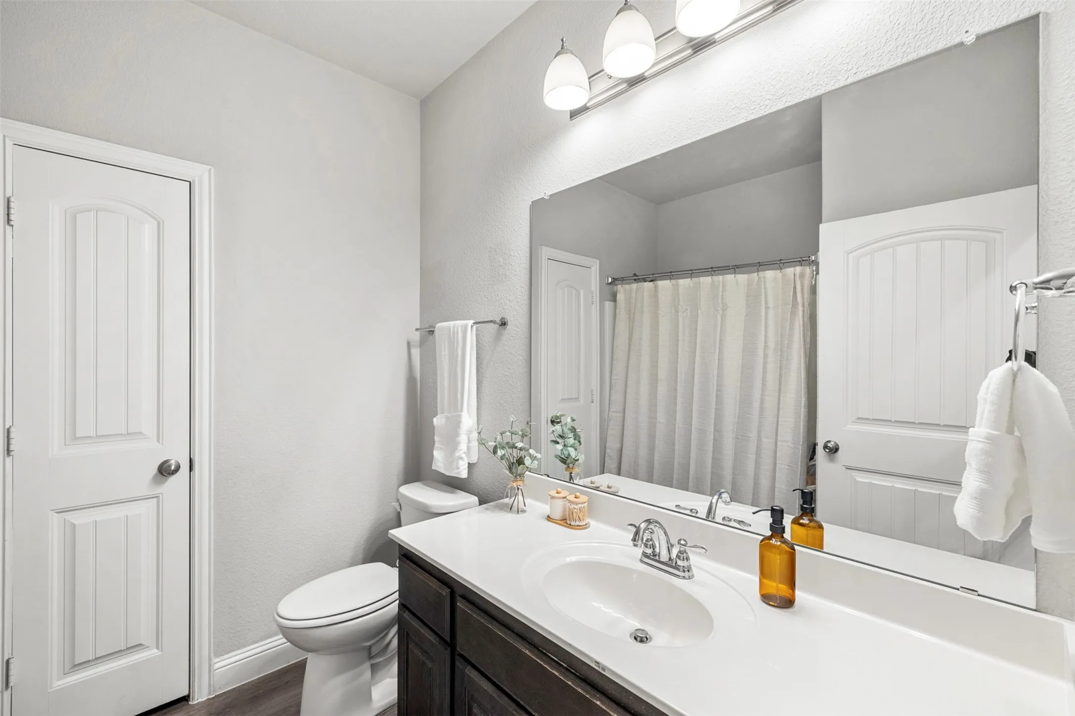 Single vanity with a white countertop and integrated sink, chrome faucet, and dark wood-finish cabinetry