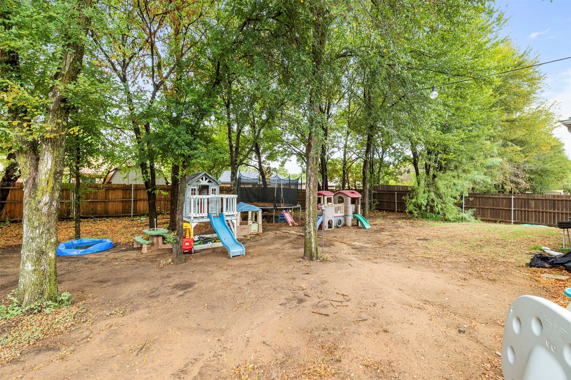 Expansive outdoor space featuring mature trees and wood fencing