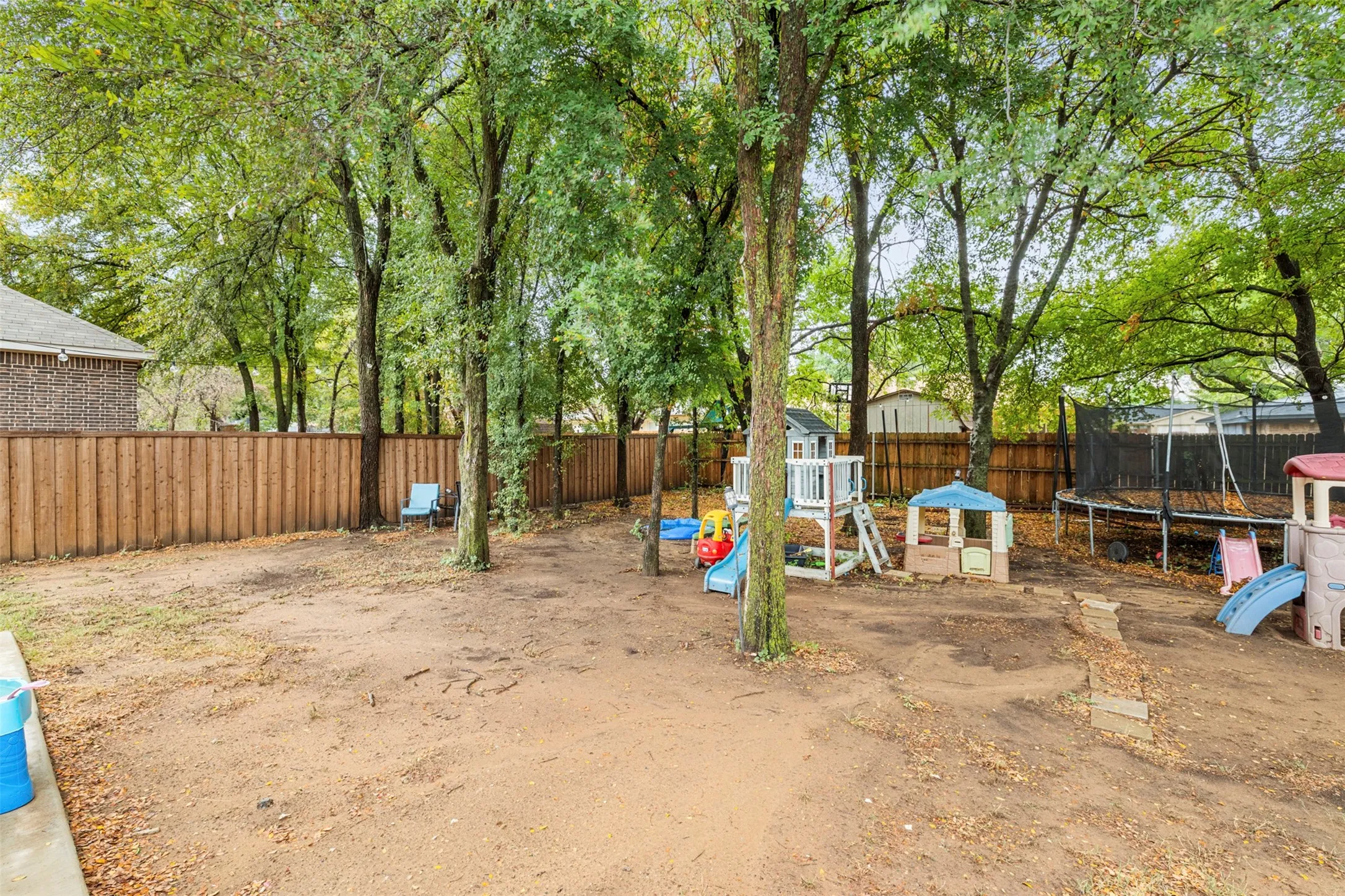 Expansive backyard featuring mature trees and wood fencing