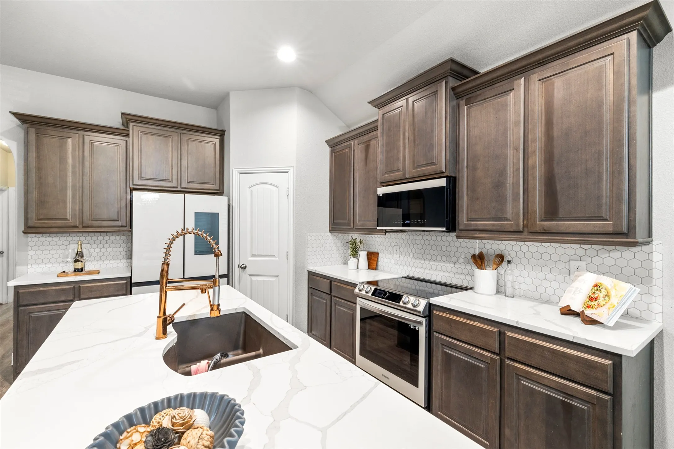 Kitchen featuring a central island with an undermount sink, a gooseneck faucet, and quartz countertops
