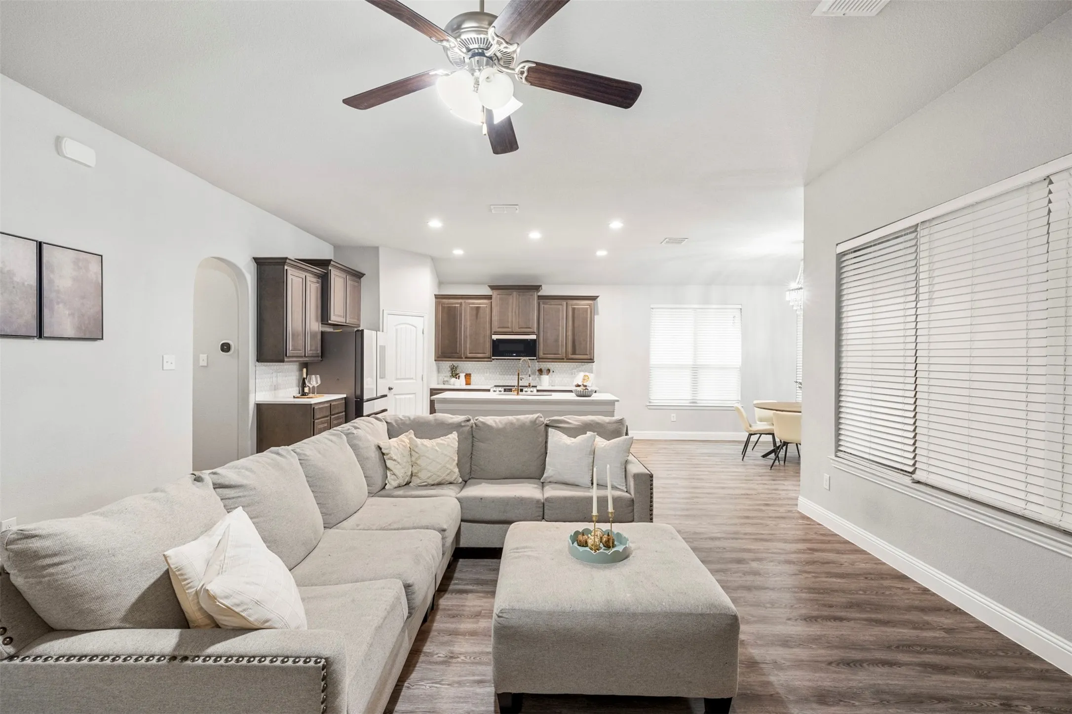 Open-concept living area with wood-finish flooring, recessed lighting, and a ceiling fan
