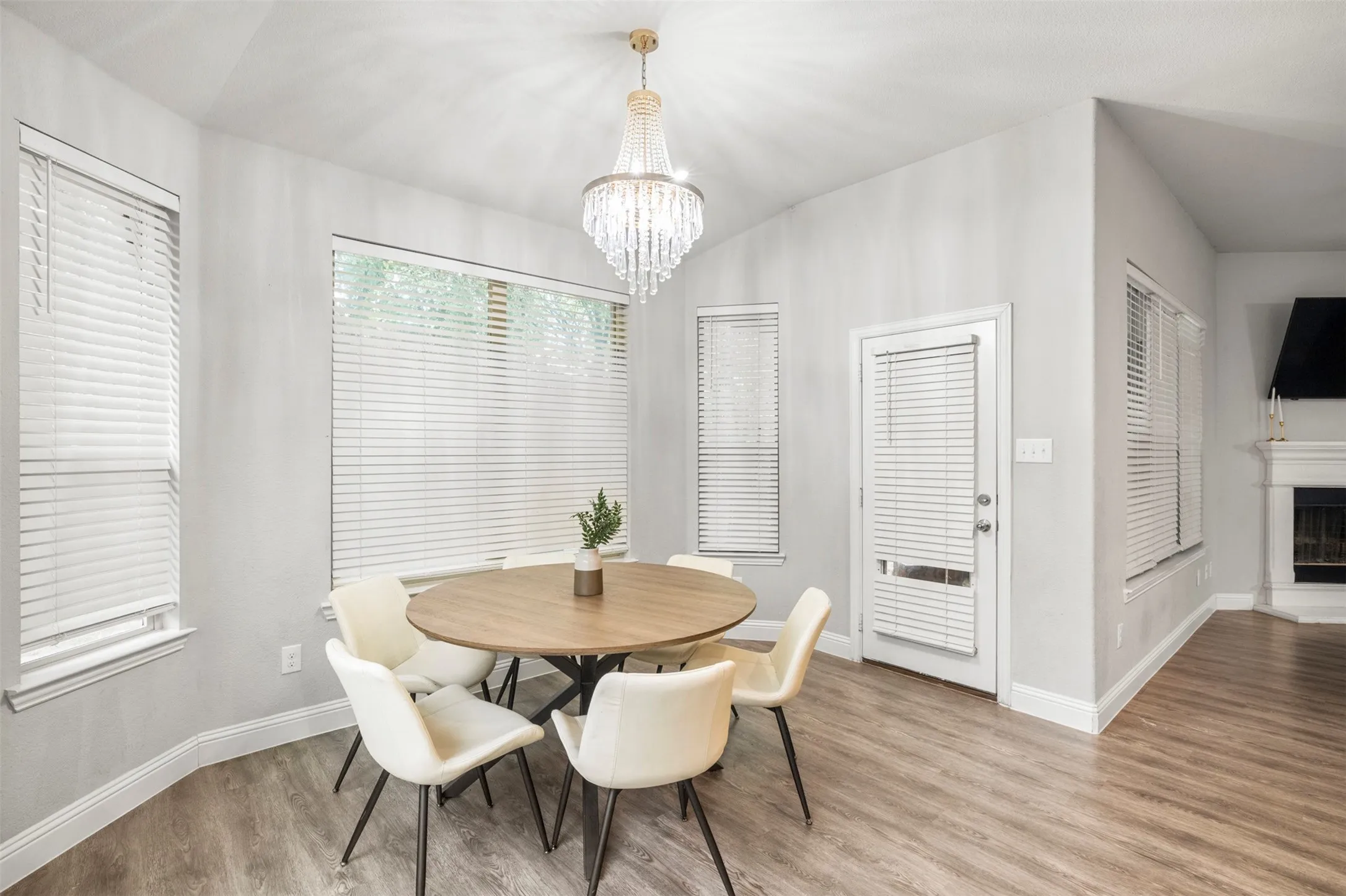 Vaulted ceiling with an elegant chandelier, multiple windows, wood-finish flooring, and white trim throughout