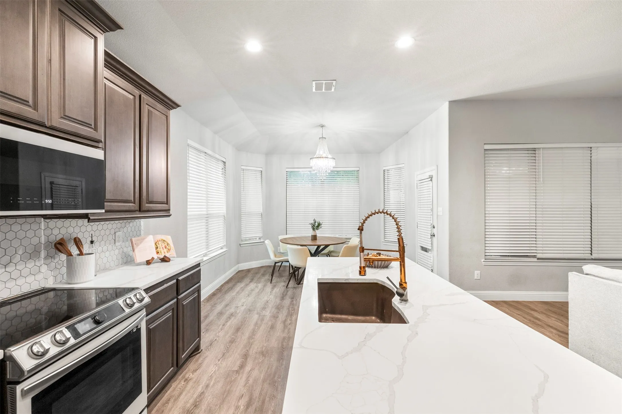 Kitchen featuring wood-finish cabinetry, white countertops, hexagon tile backsplash, and a built-in microwave