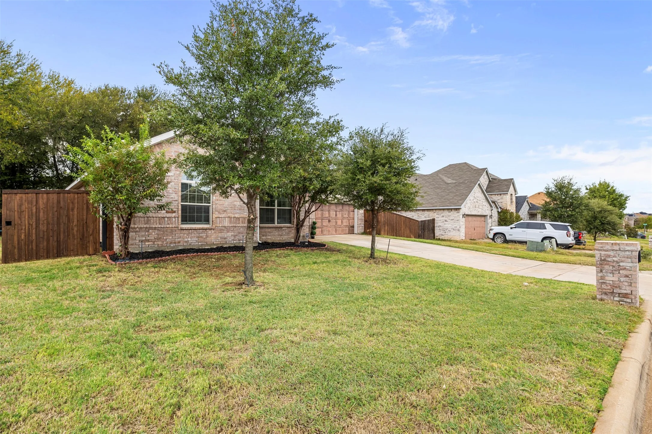 Brick exterior with multiple windows, an attached garage, and a privacy fence
