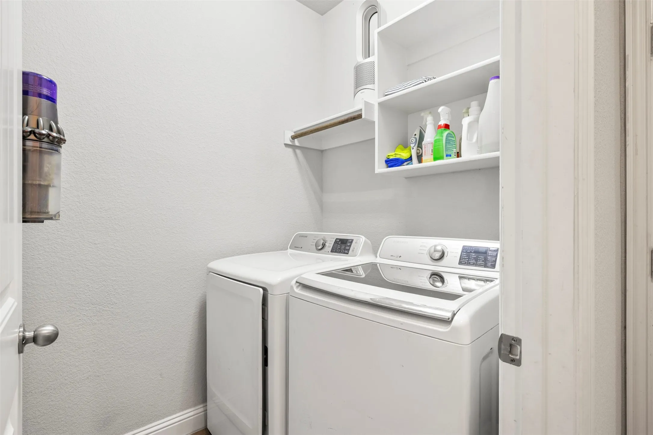 White shaker-style cabinetry, wood-finish flooring, and a wall-mounted clothing rod