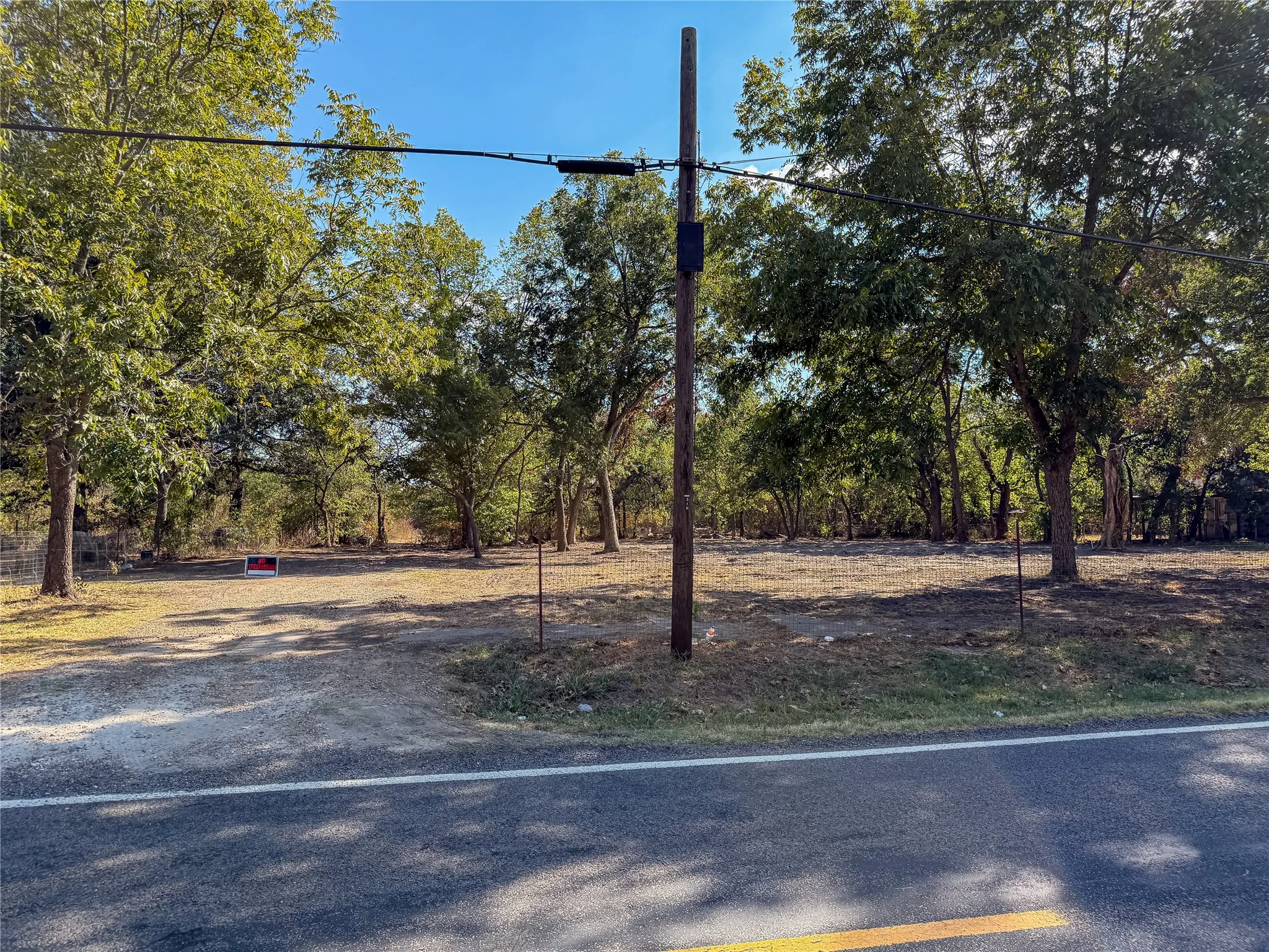 Roadside property featuring mature trees and a cleared, level lot