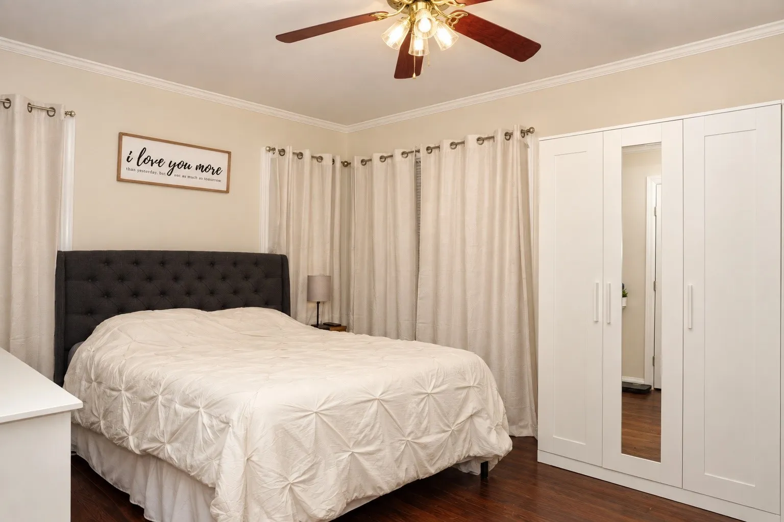 Wood-finish flooring, crown molding, and a ceiling fan with integrated lighting