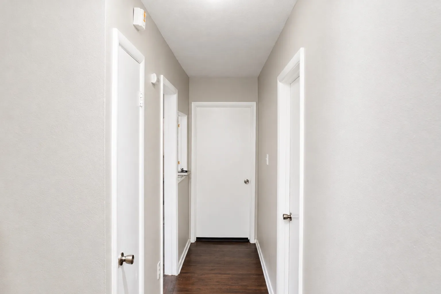 Wood-finish flooring with light-toned walls and multiple white doors
