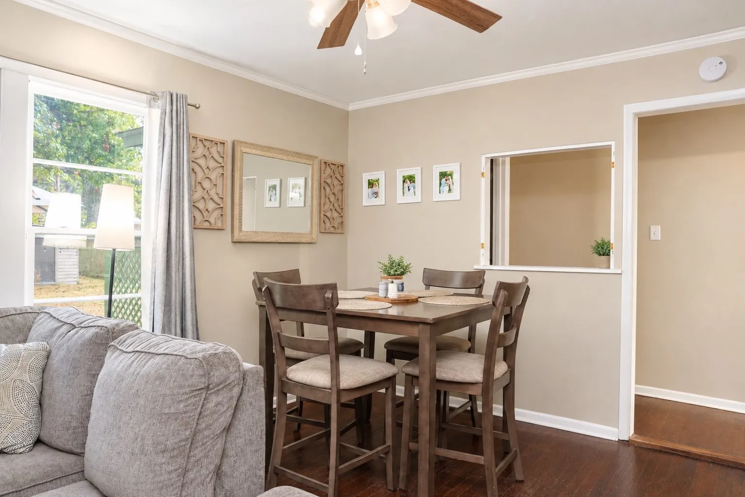 Hardwood-style flooring, crown molding, white trim, and a pass-through opening