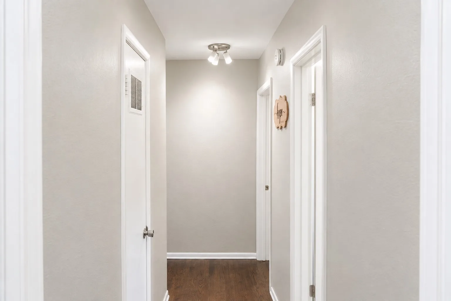 Hallway featuring wood-finish flooring, light-toned walls, and white trim