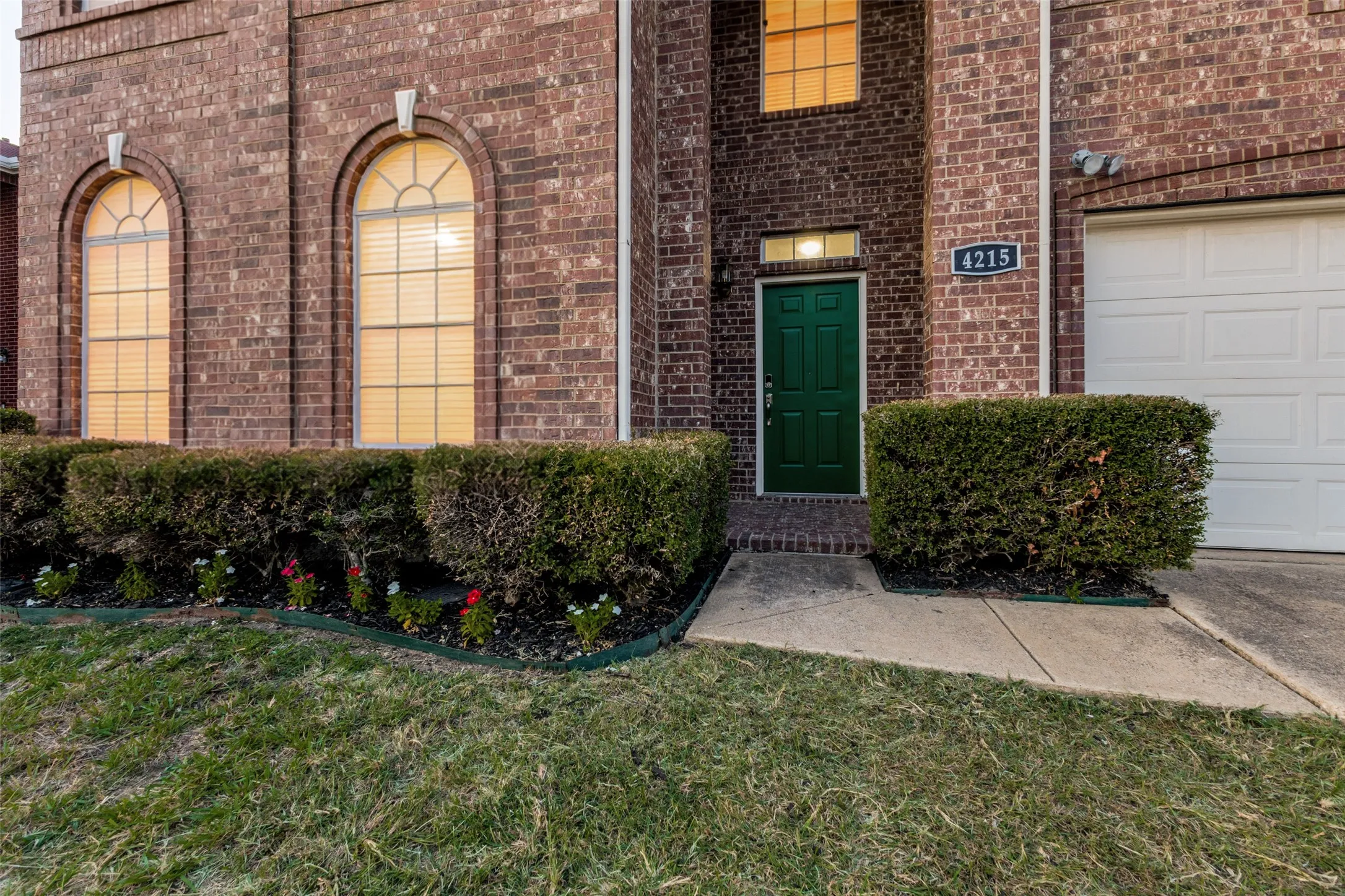 Brick facade with arched windows, a green front door, and an attached garage