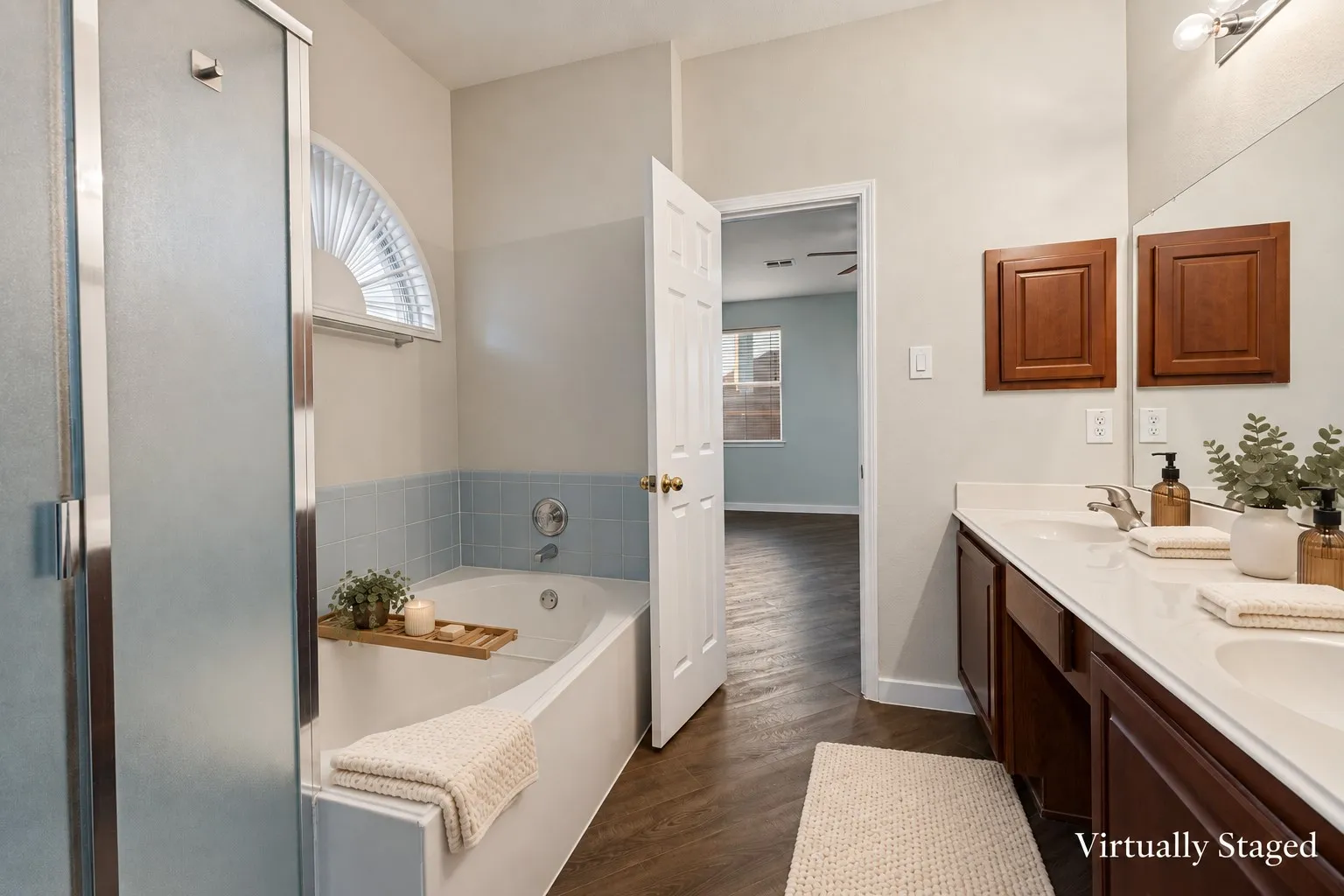 Primary bathroom featuring a built-in tub, a frosted glass shower enclosure, a double vanity with an integrated countertop, and wood-finish flooring