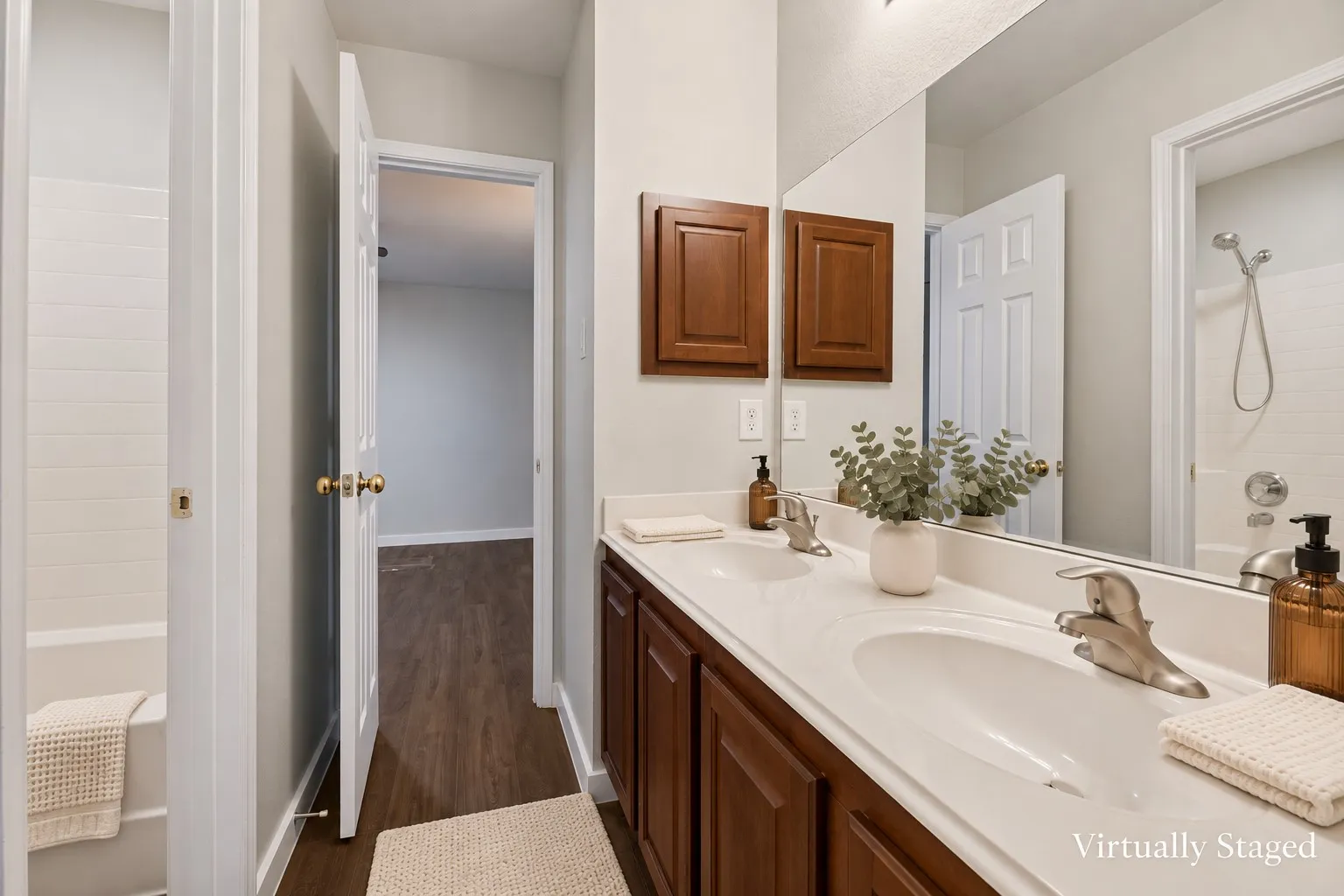 Dual vanity with integrated sinks and brushed nickel faucets, wood-finish cabinetry, and a full-width mirror