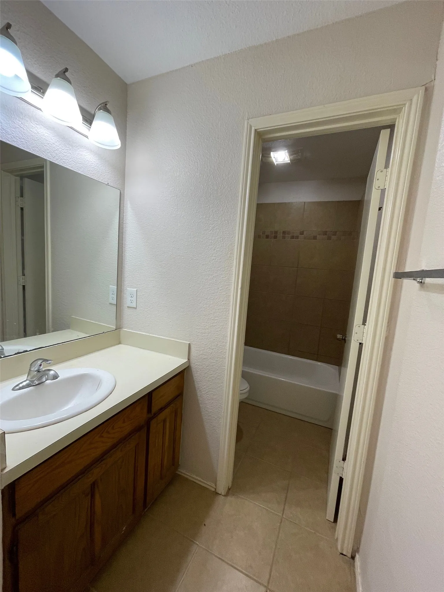 Bathroom vanity with wood-finish cabinetry, a single basin sink, and a light-colored countertop