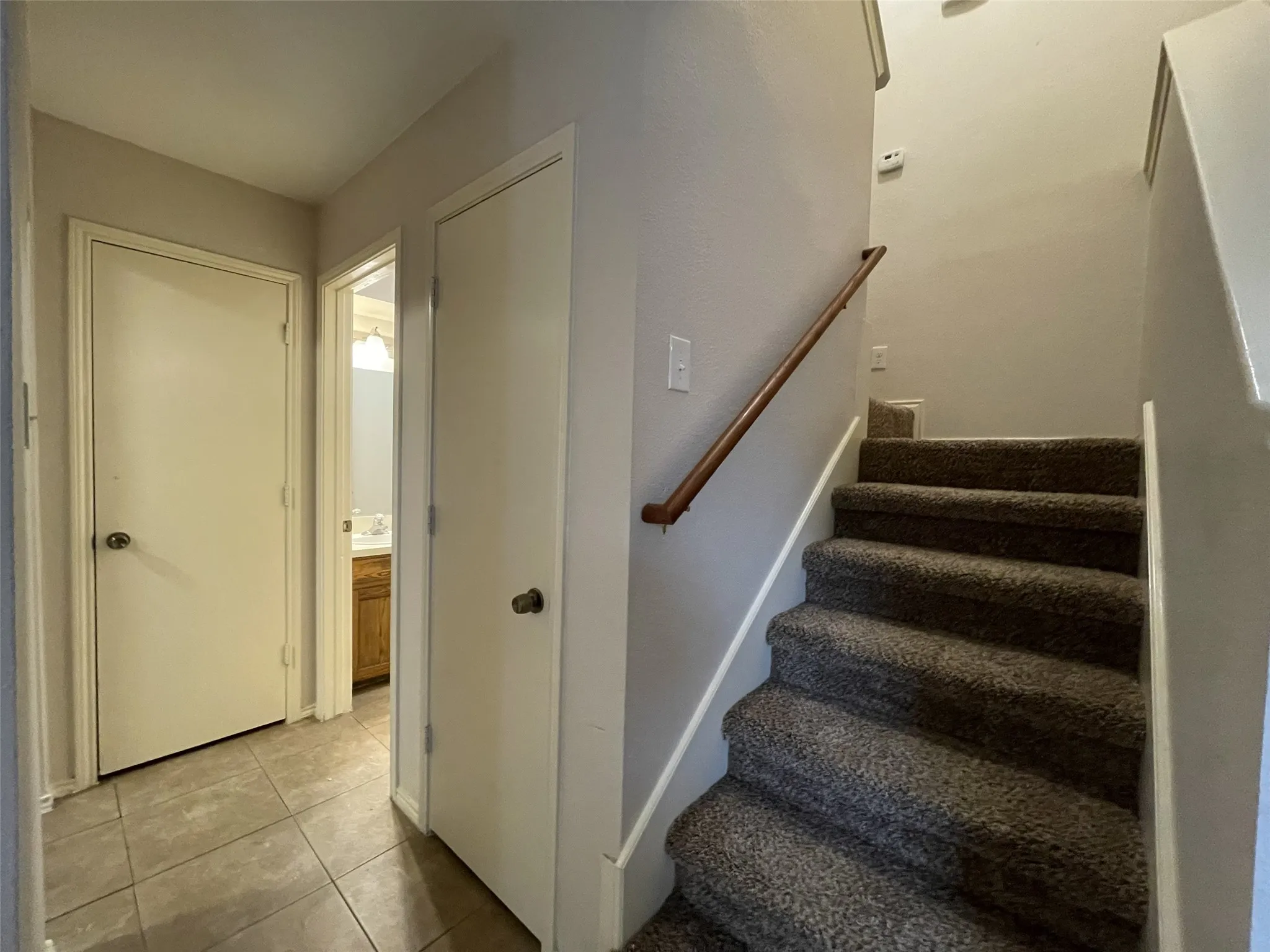 Carpeted staircase with wooden handrail