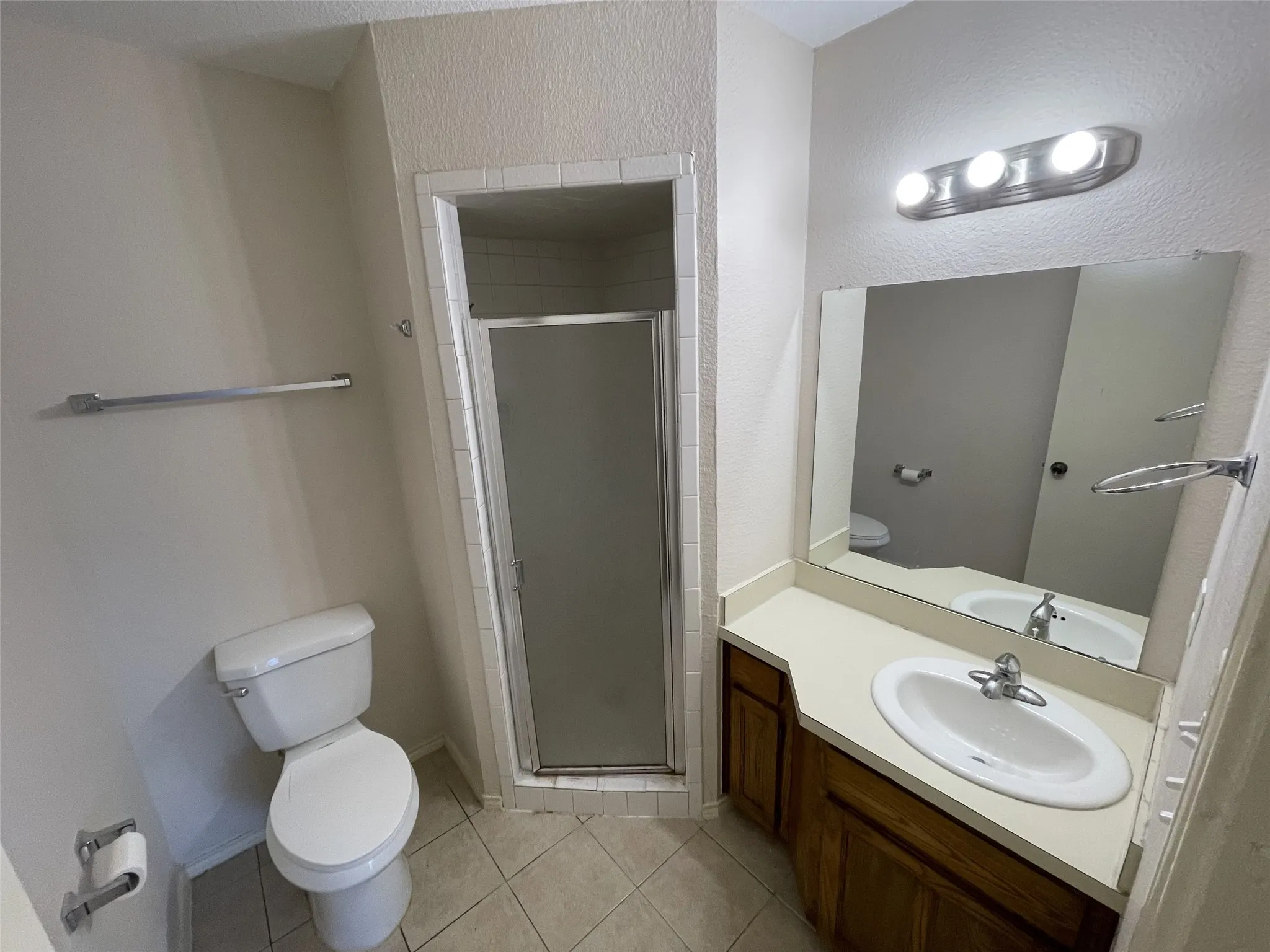 Tiled flooring complementing a built-in vanity with an integrated sink, polished chrome faucet, and expansive mirror