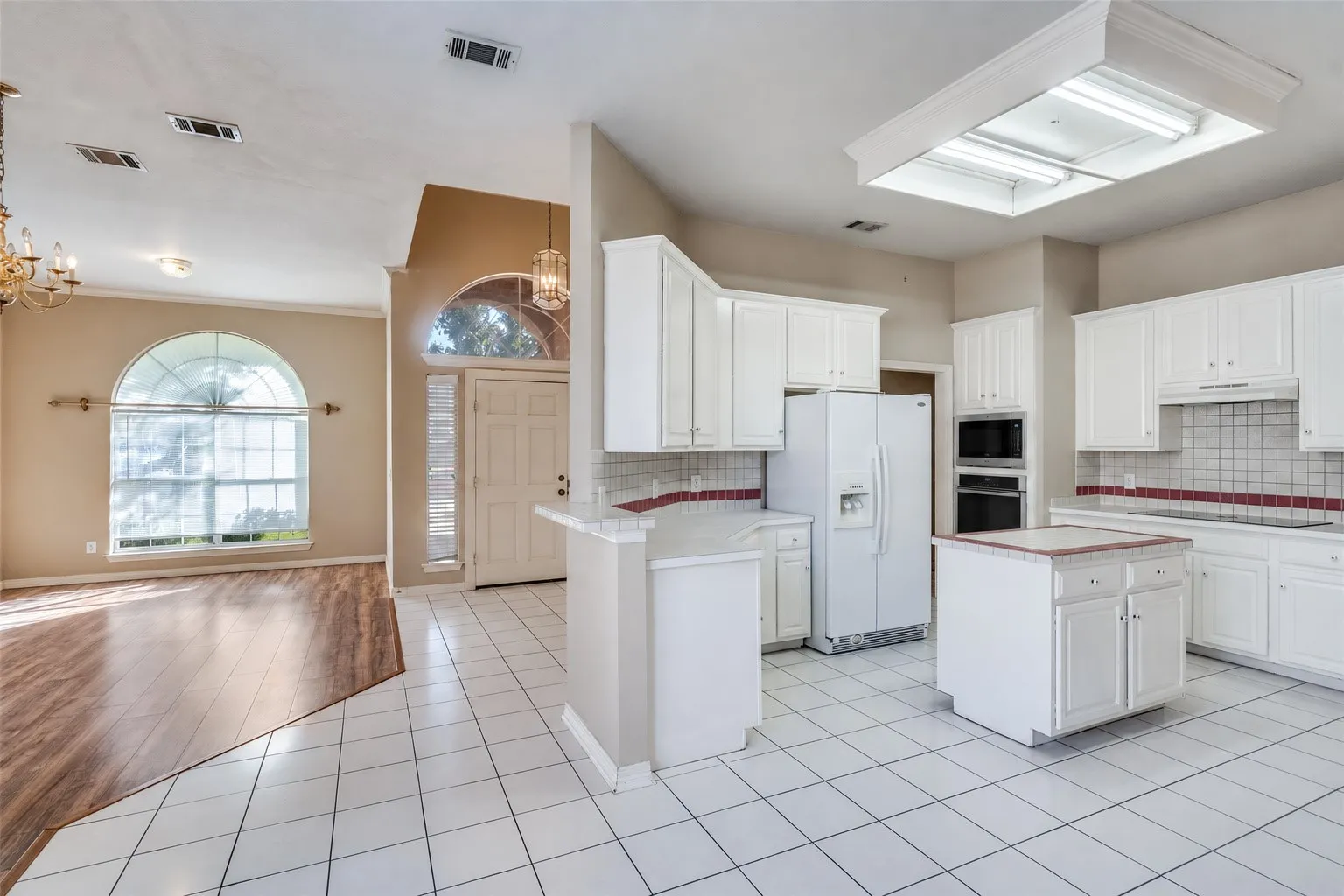 Kitchen featuring white cabinetry, a central island, and white tile flooring