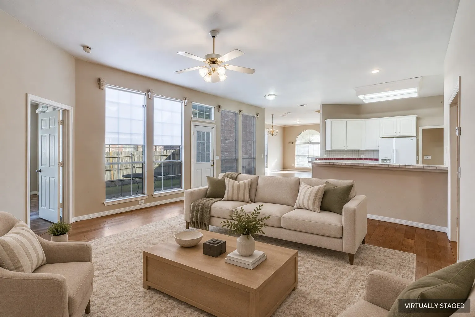 Wood-finish flooring, ceiling fan, recessed lighting, white cabinetry, and a kitchen pass-through