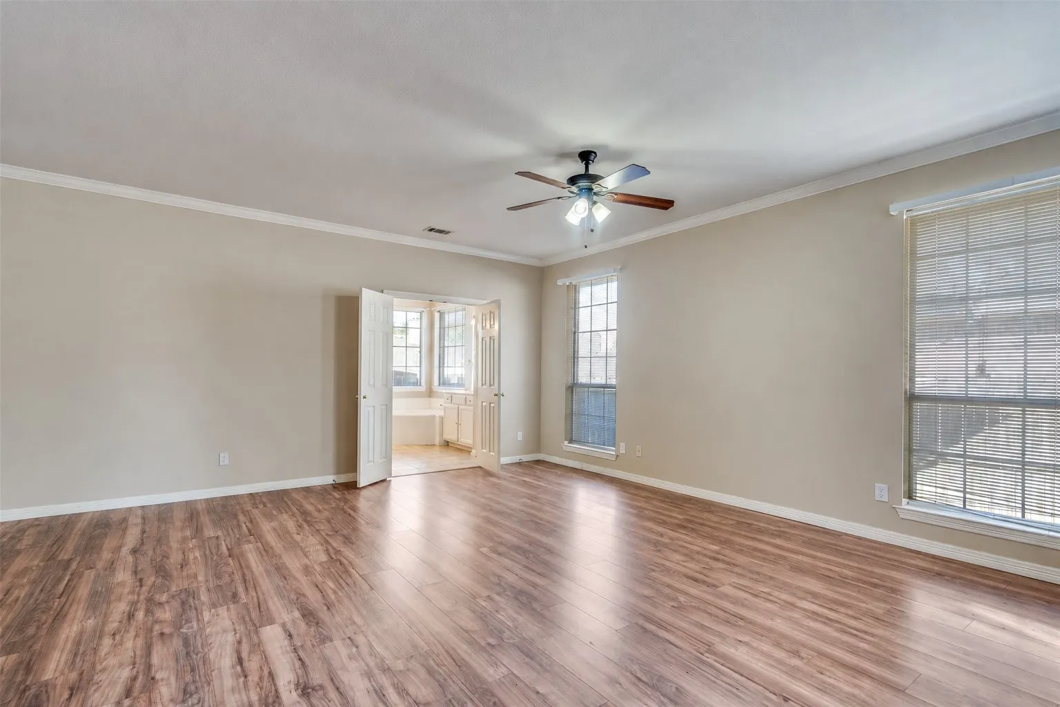 Wood-finish flooring, crown molding, double pane windows, and a ceiling fan