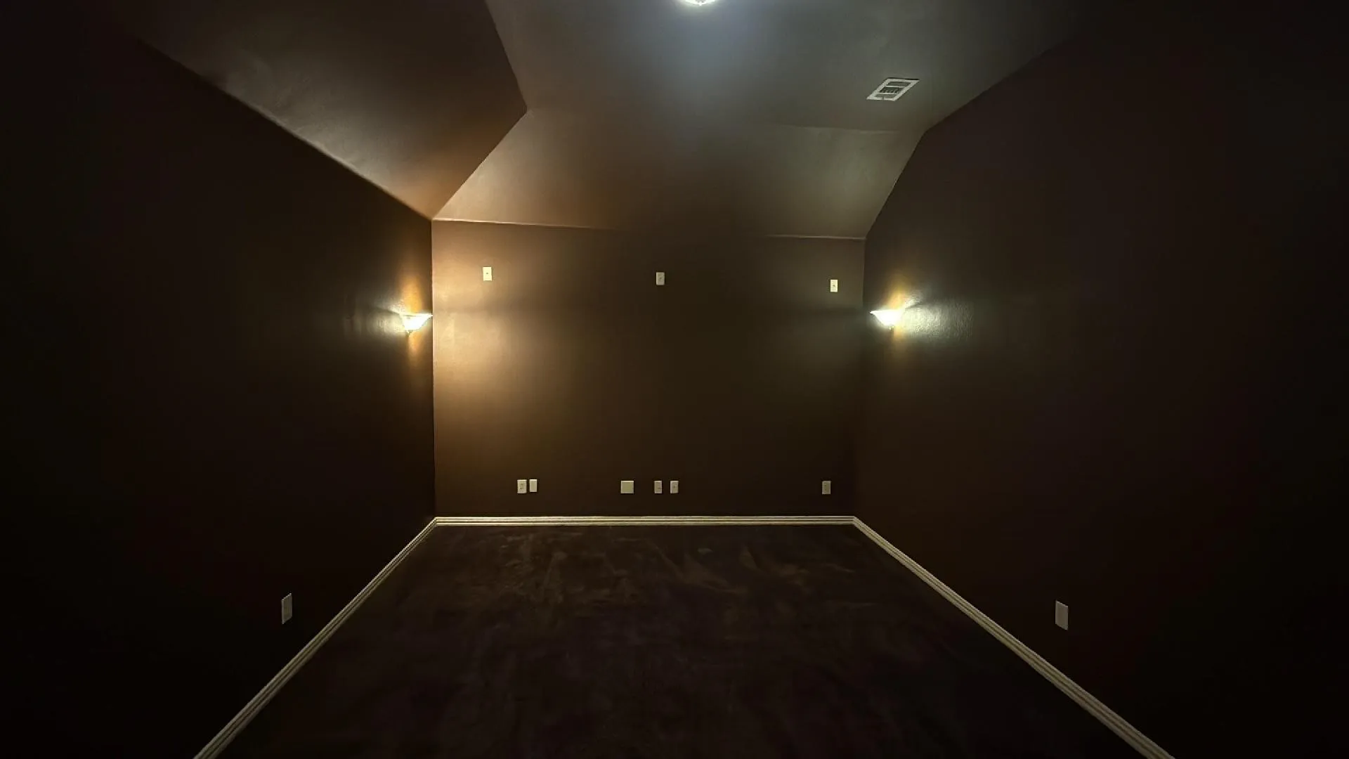 Carpeted room with dark walls, featuring recessed ceiling lighting, wall sconces, and sloped ceilings