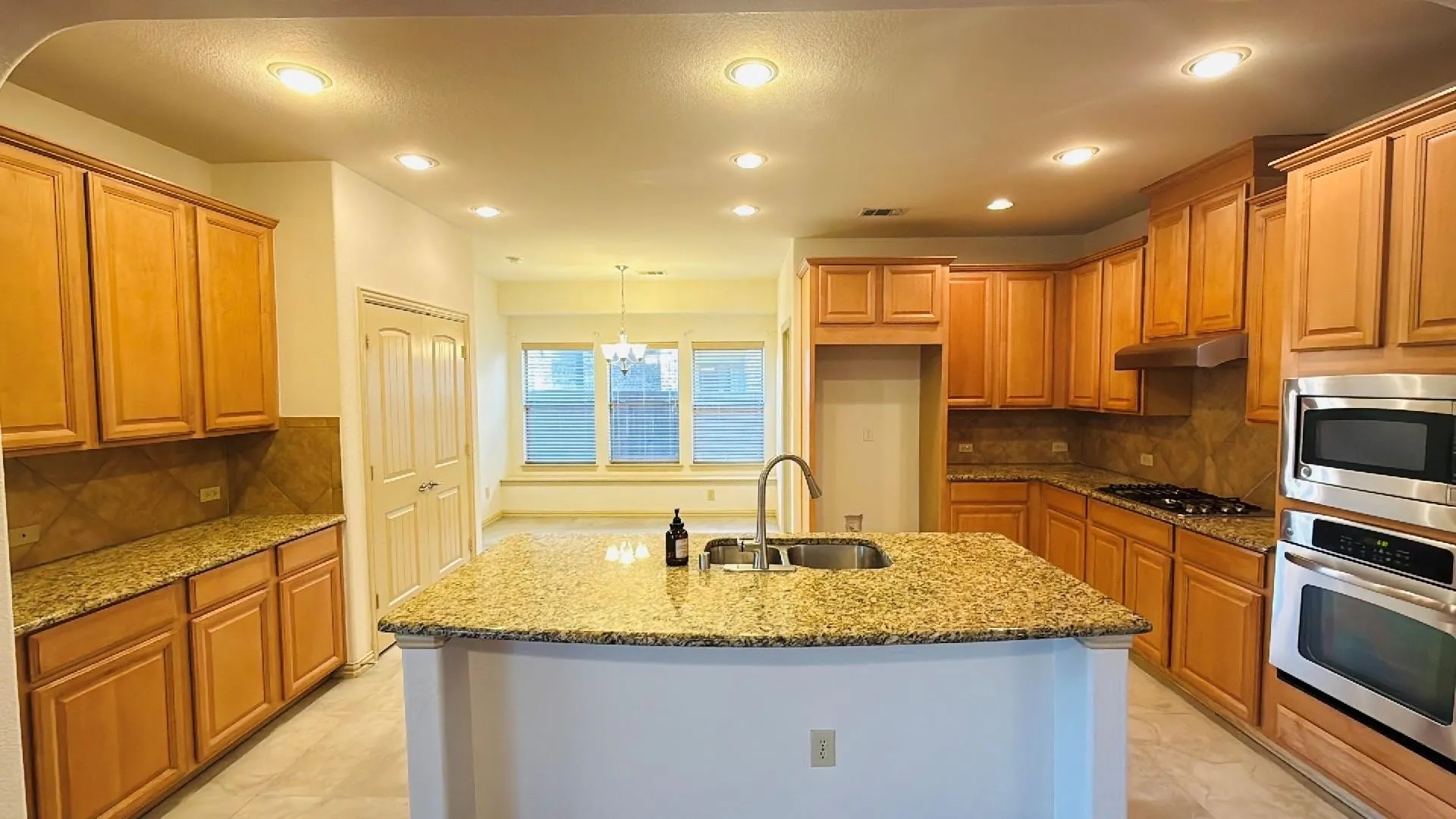 Kitchen featuring granite countertops, wood cabinetry, stainless steel appliances, and recessed​​‌​​​​‌​​‌‌​‌‌​​​‌‌​‌​‌​‌​​​‌​​ lighting
