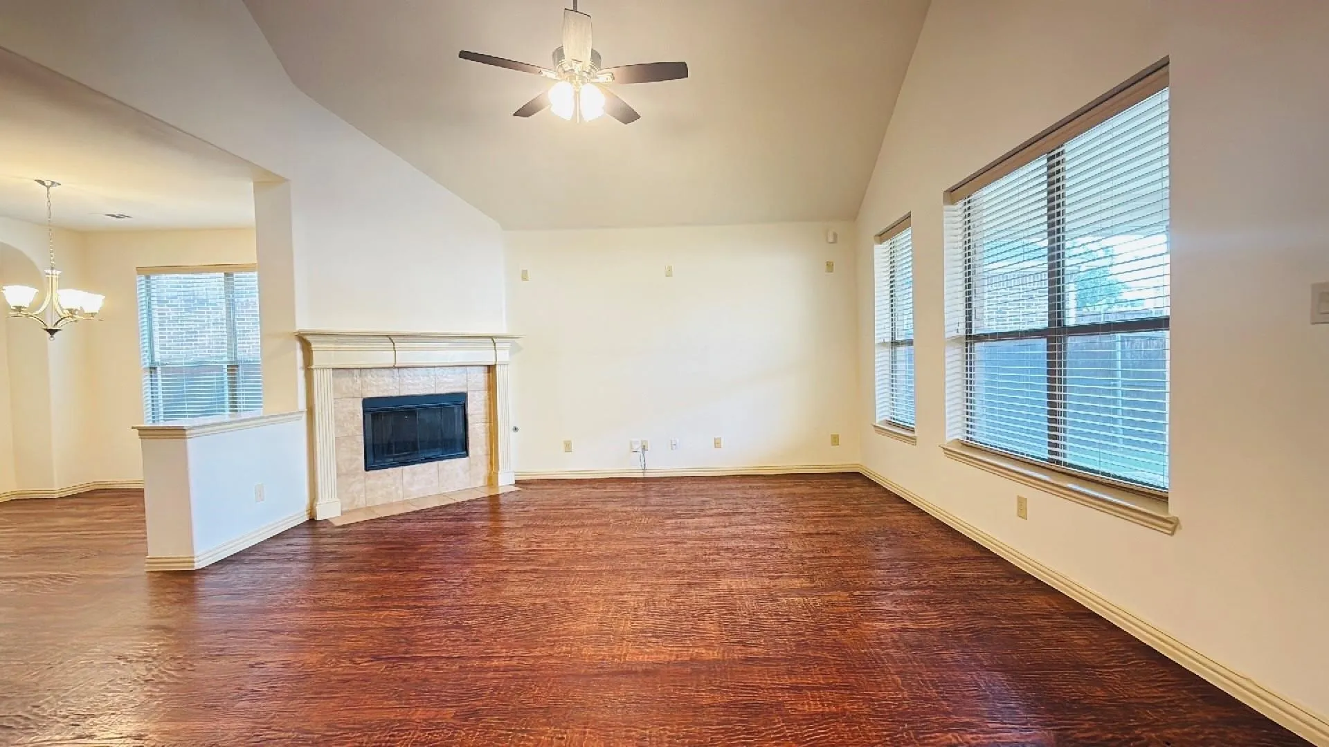 Varnished wood-finish flooring, vaulted ceiling, and a ceiling fan