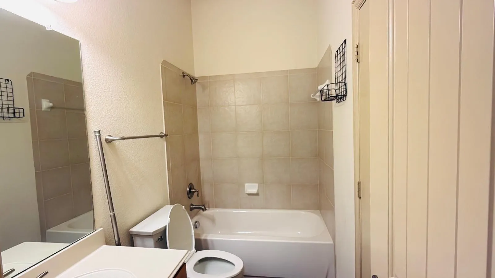 Bathroom featuring an integrated bathtub and shower, tiled shower surround, built-in vanity with sink, and a framed mirror