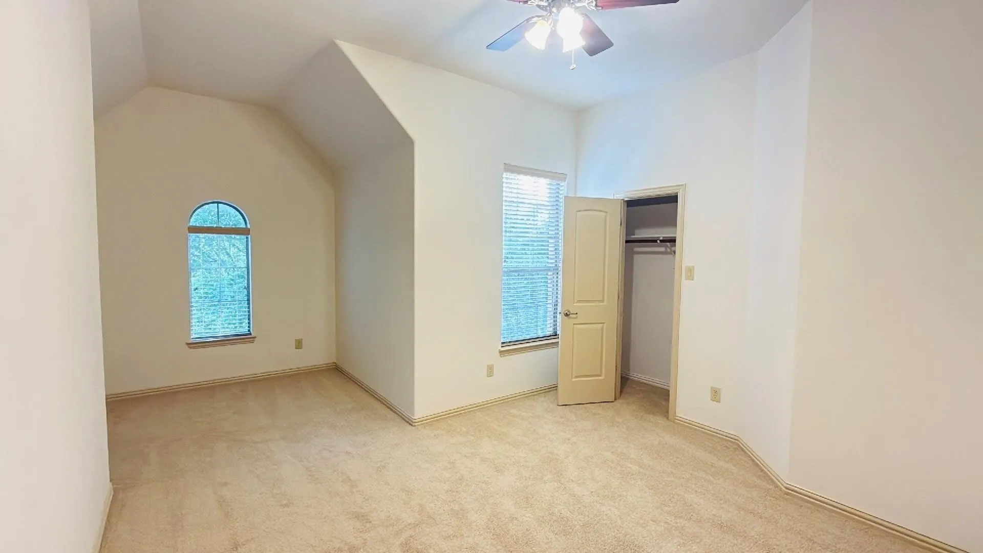 Carpeted room featuring a ceiling fan with integrated lighting, a standard window with horizontal blinds, and a built-in closet with a bi-fold door
