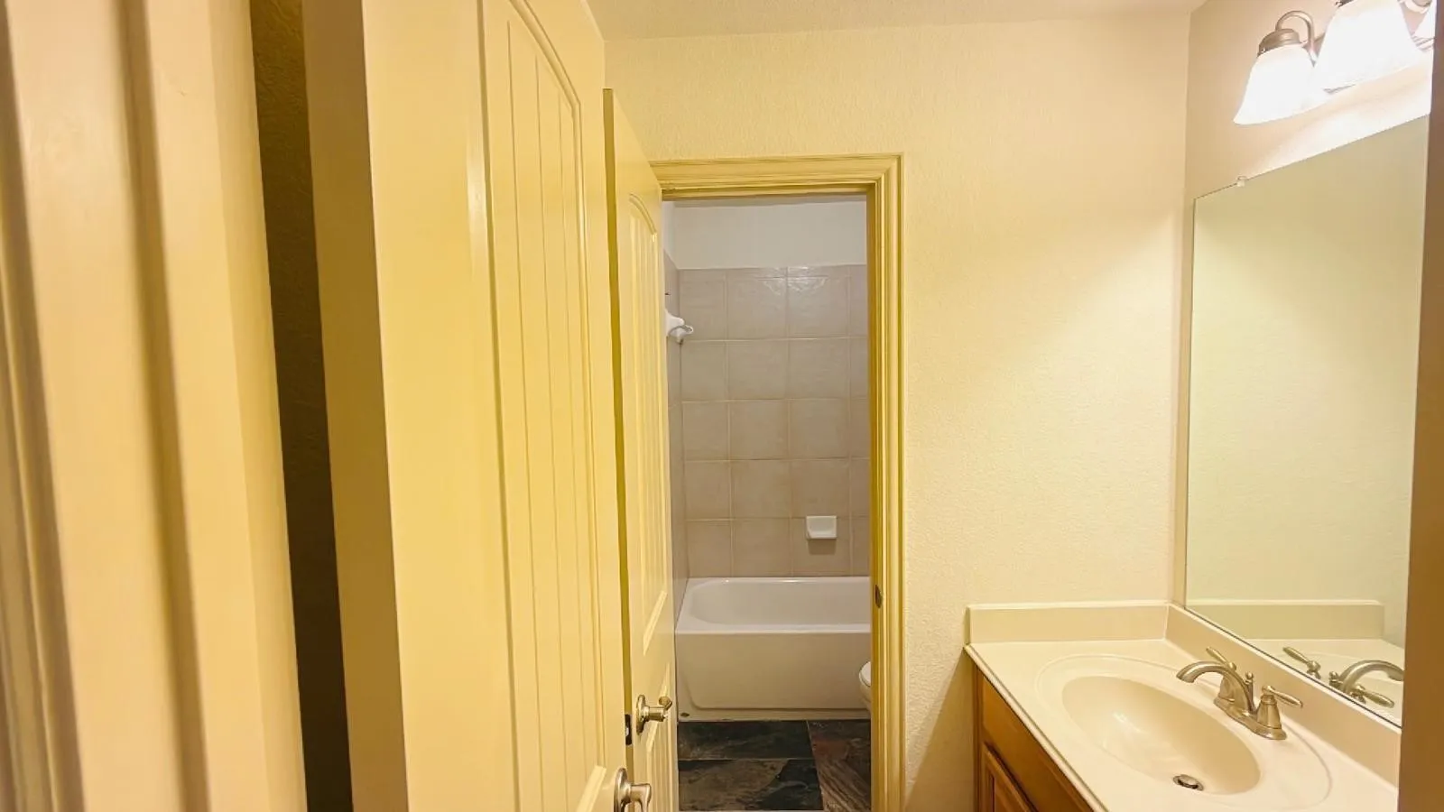 Vanity with an integrated sink, polished chrome faucet, and expansive mirror