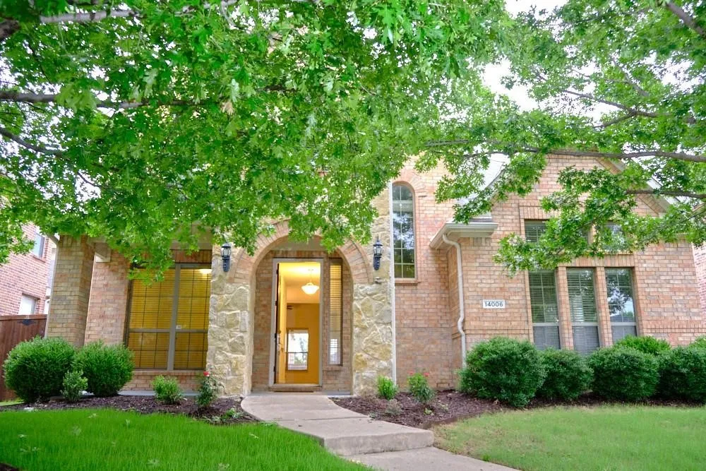 Brick exterior with stone accents, arched entryway, and mature trees