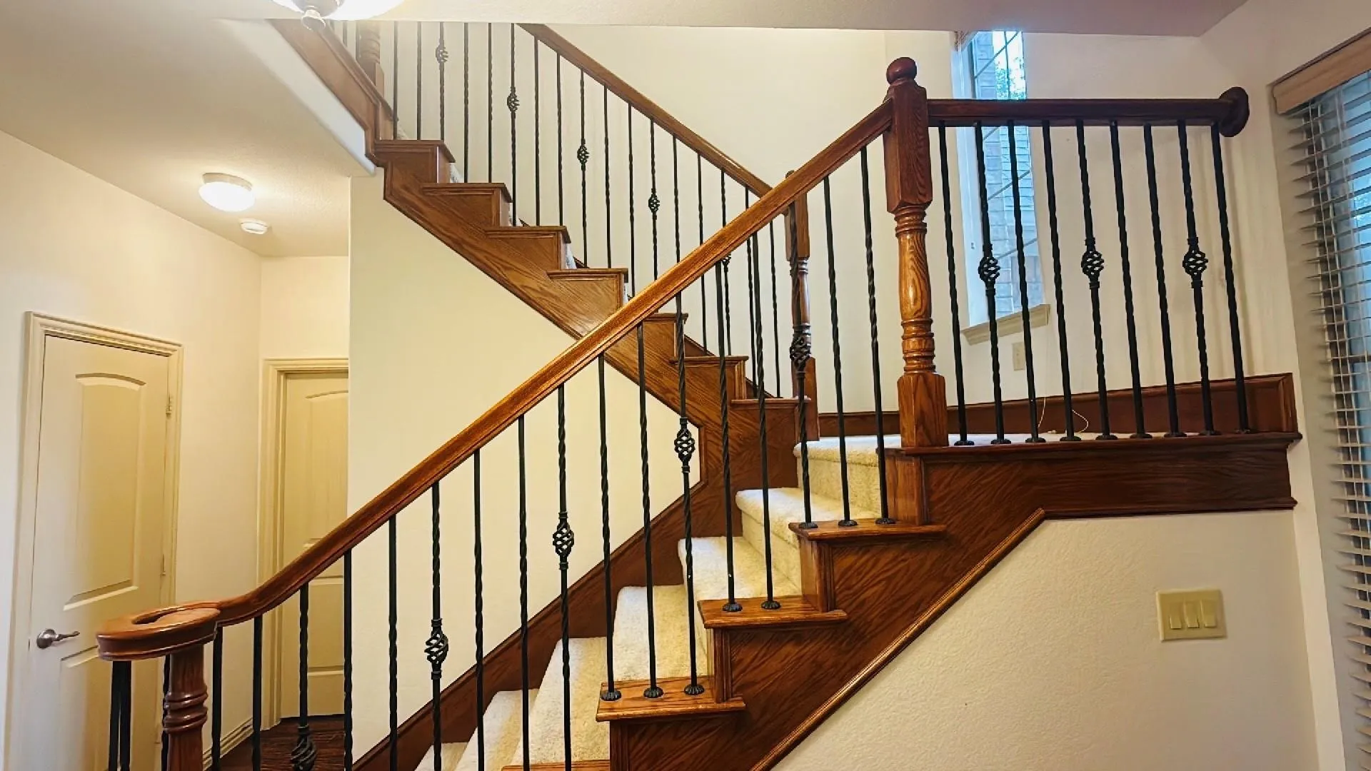 Staircase featuring wood treads, carpet runners, and wrought iron balusters