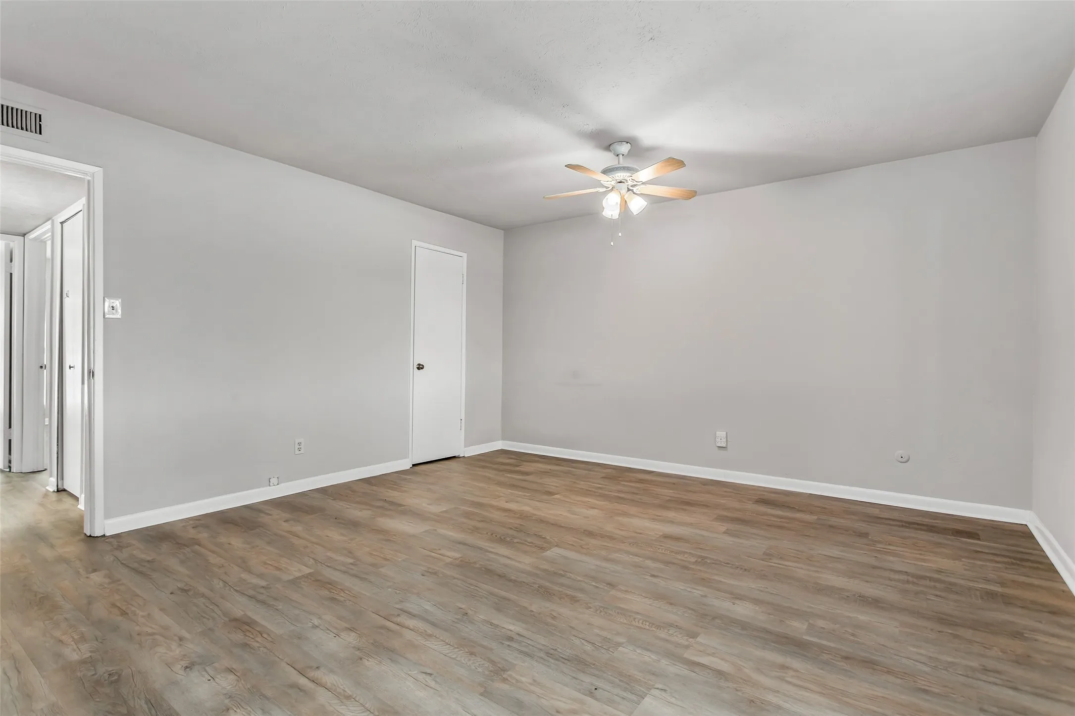 Wood-finish flooring with light gray walls, white trim, and a ceiling fan with integrated lighting