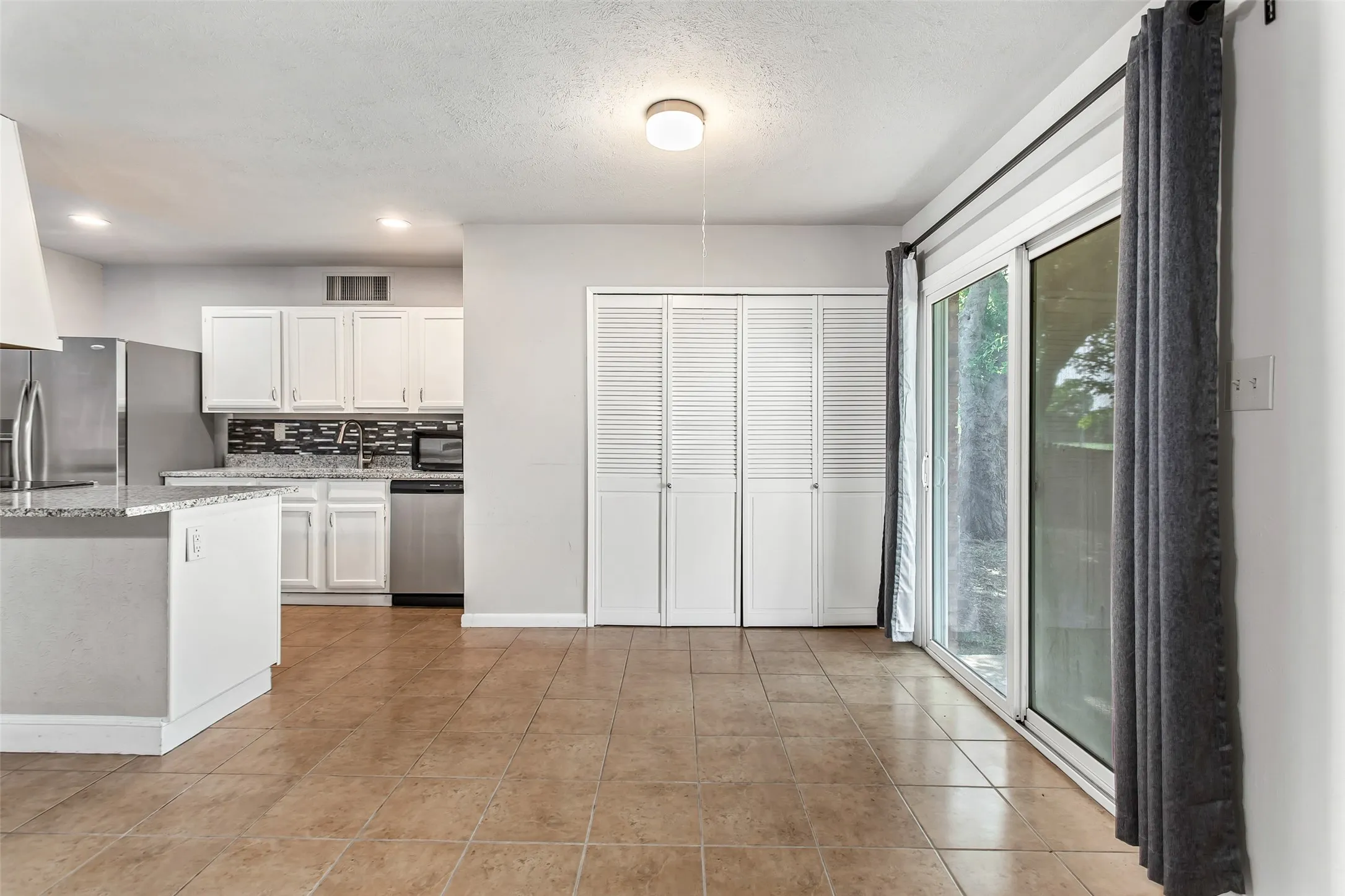 Kitchen with white cabinetry, stainless steel appliances, and a tiled backsplash