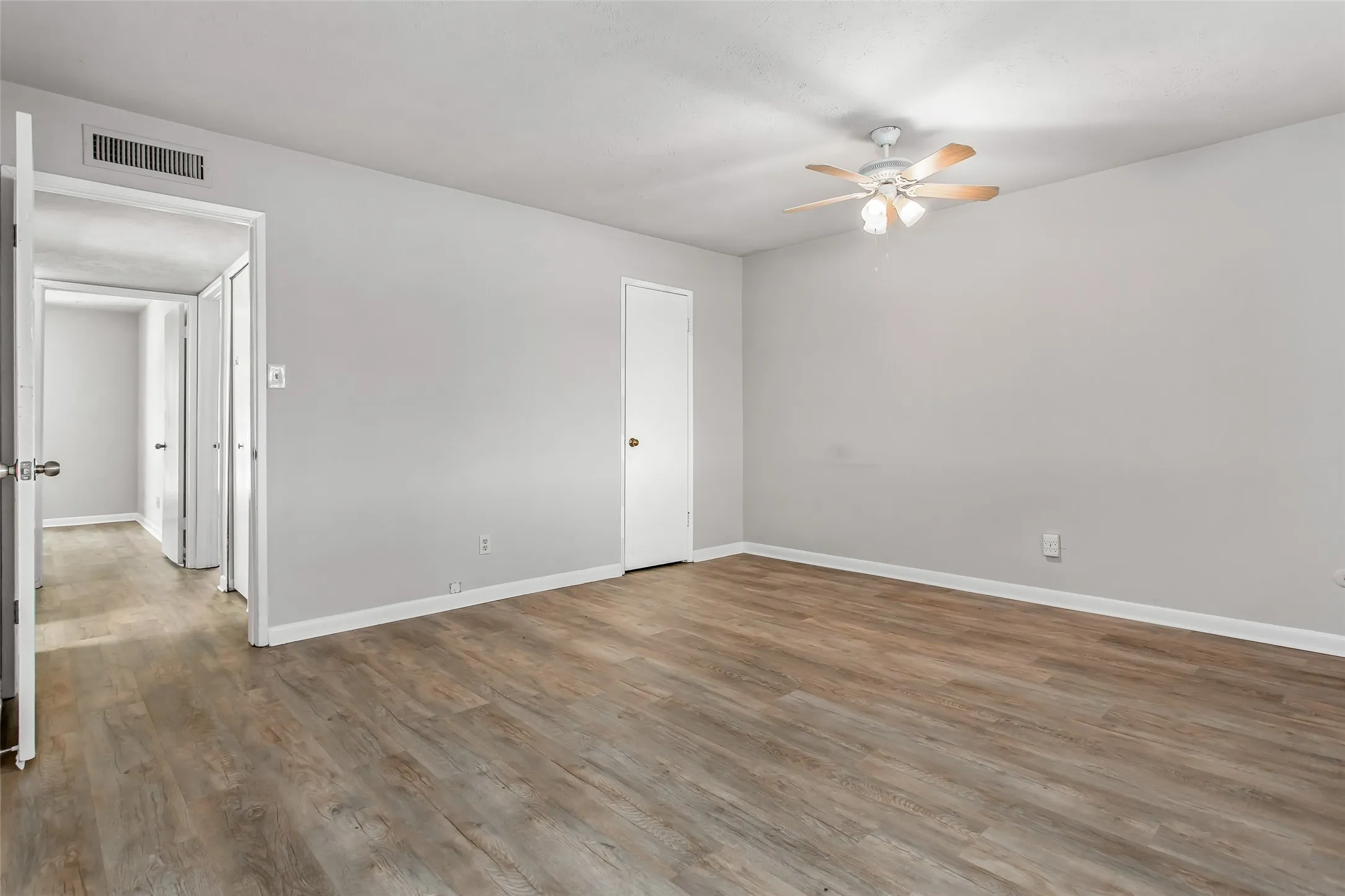 Wood-finish flooring throughout, light gray wall finishes, and a ceiling fan with integrated lighting