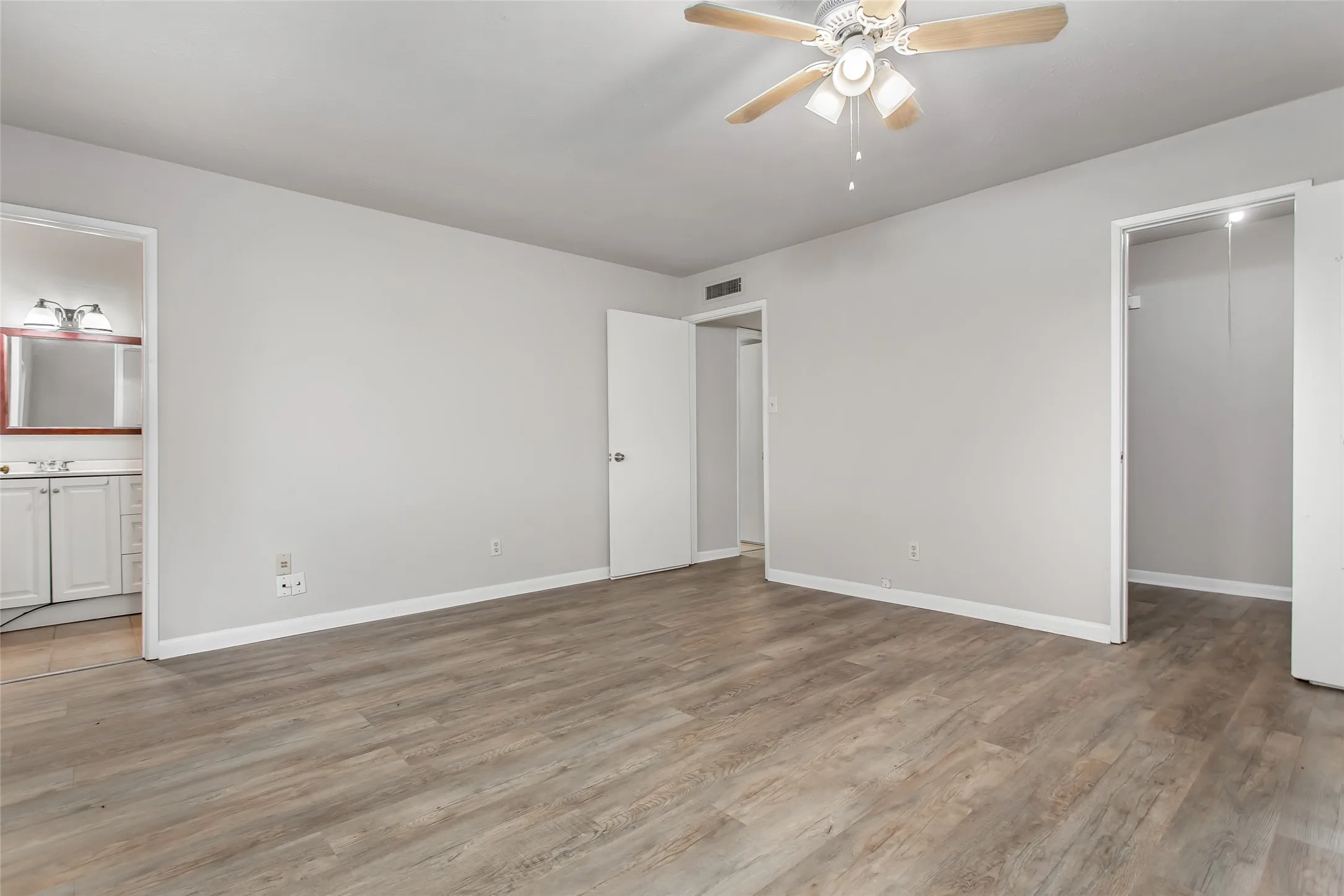 Wood-finish flooring throughout, neutral wall tones, and a ceiling fan with integrated lighting